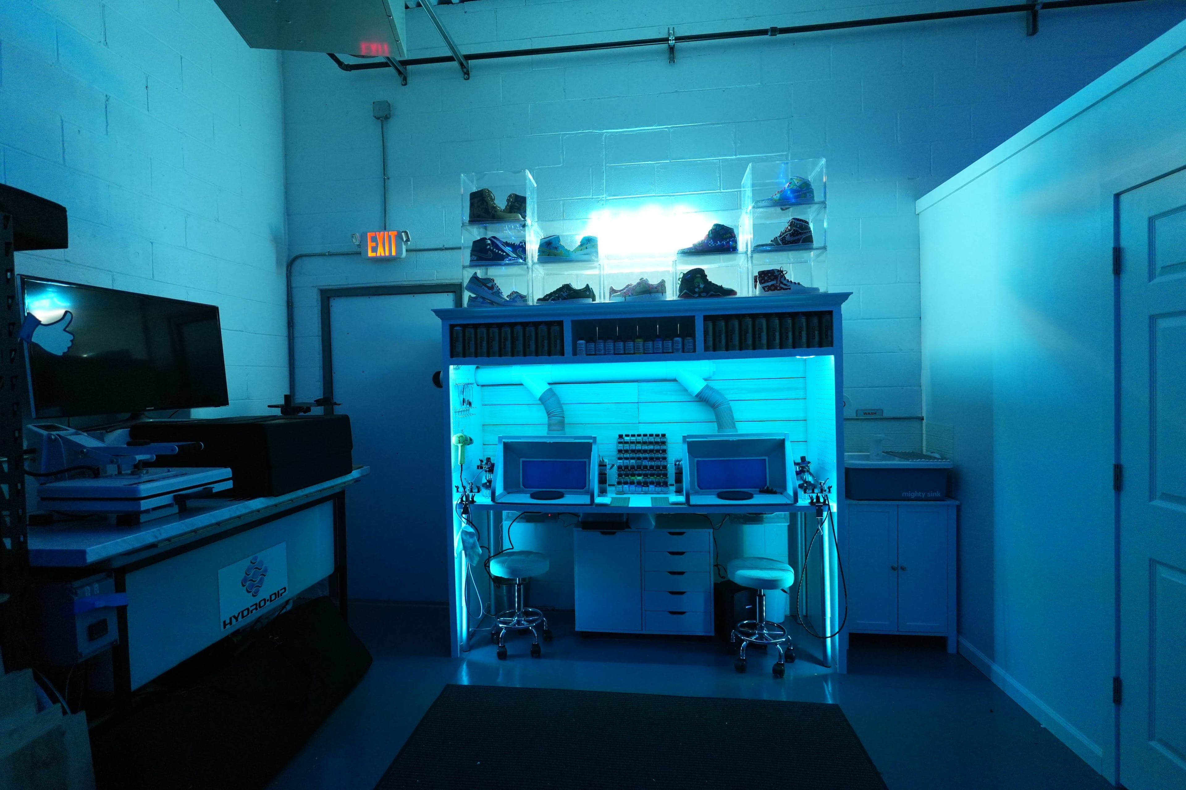 The image shows a modern workspace with two computers on a desk, surrounded by storage cabinets and illuminated by blue lighting.