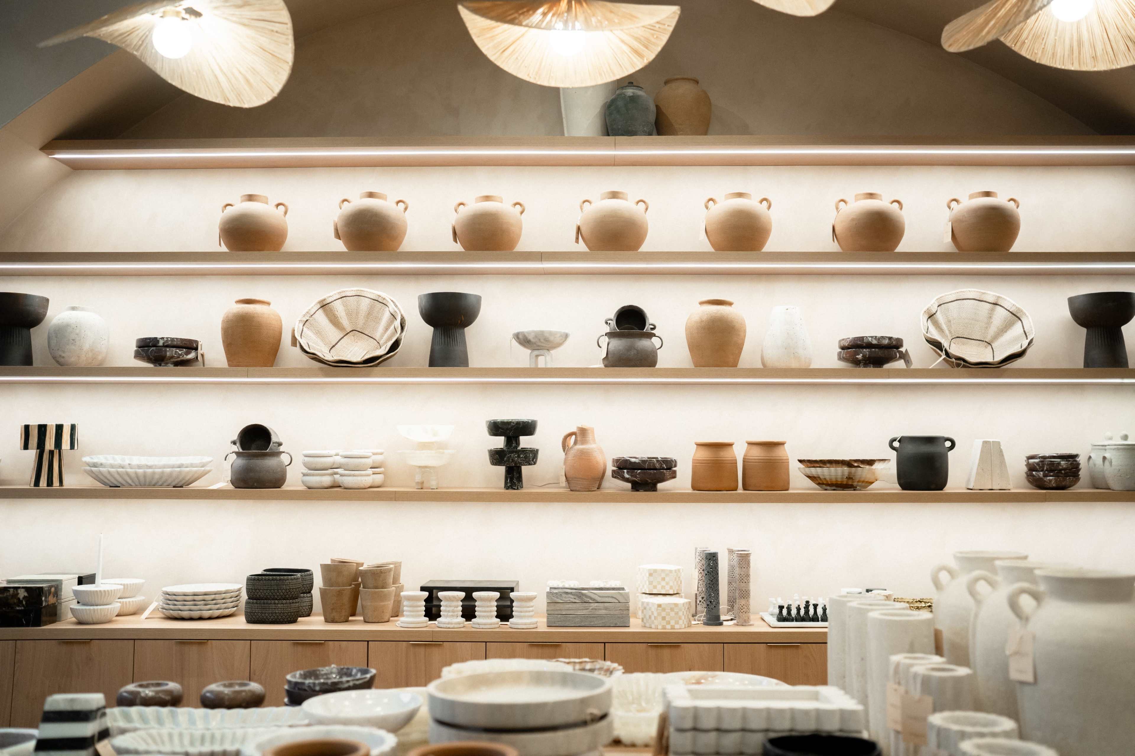 A series of shelves displays an array of pottery and ceramic items in various shapes and colors.