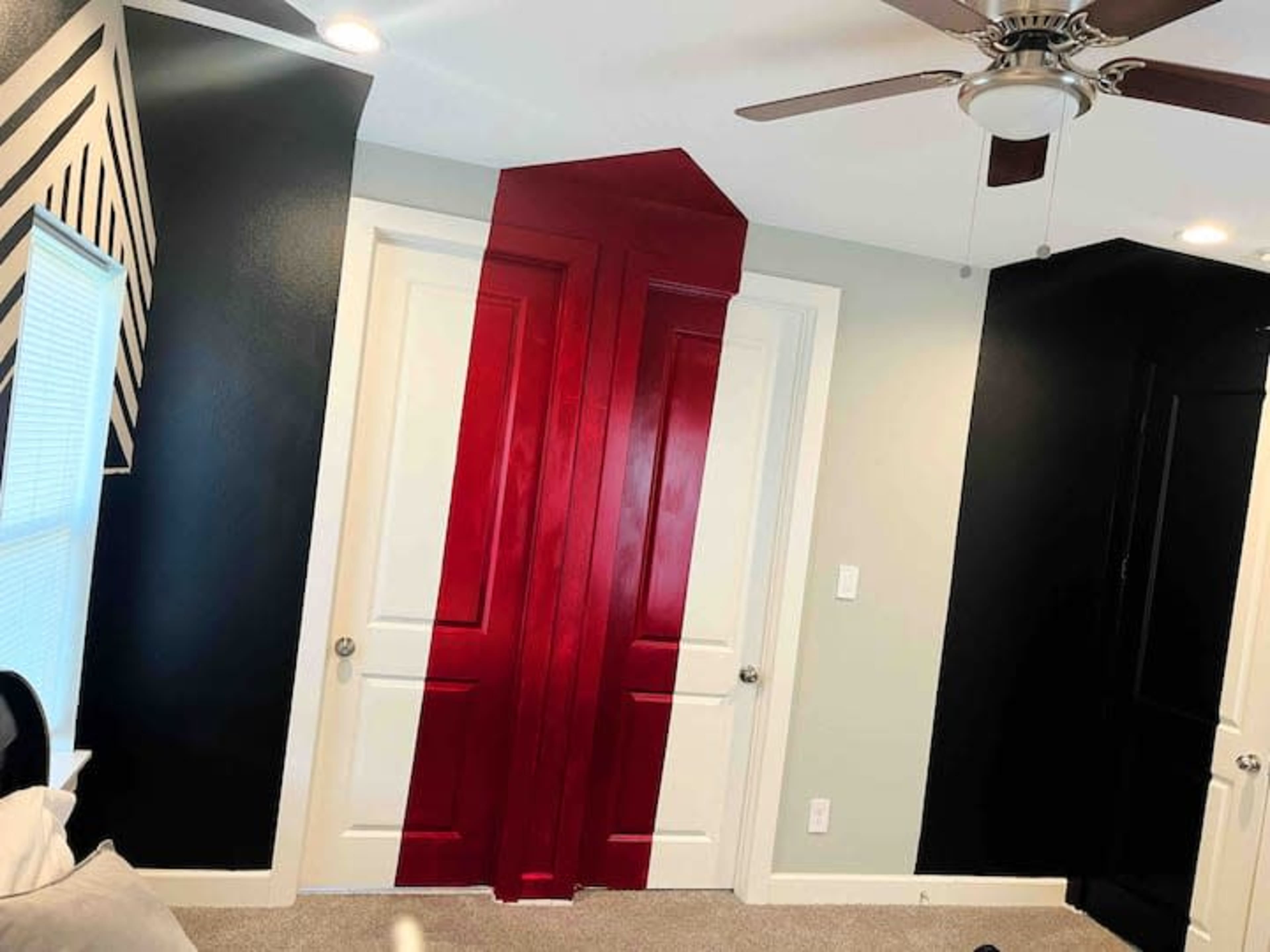 The image shows a room with two white doors partially painted in a red color, contrasting with black and grey walls.
