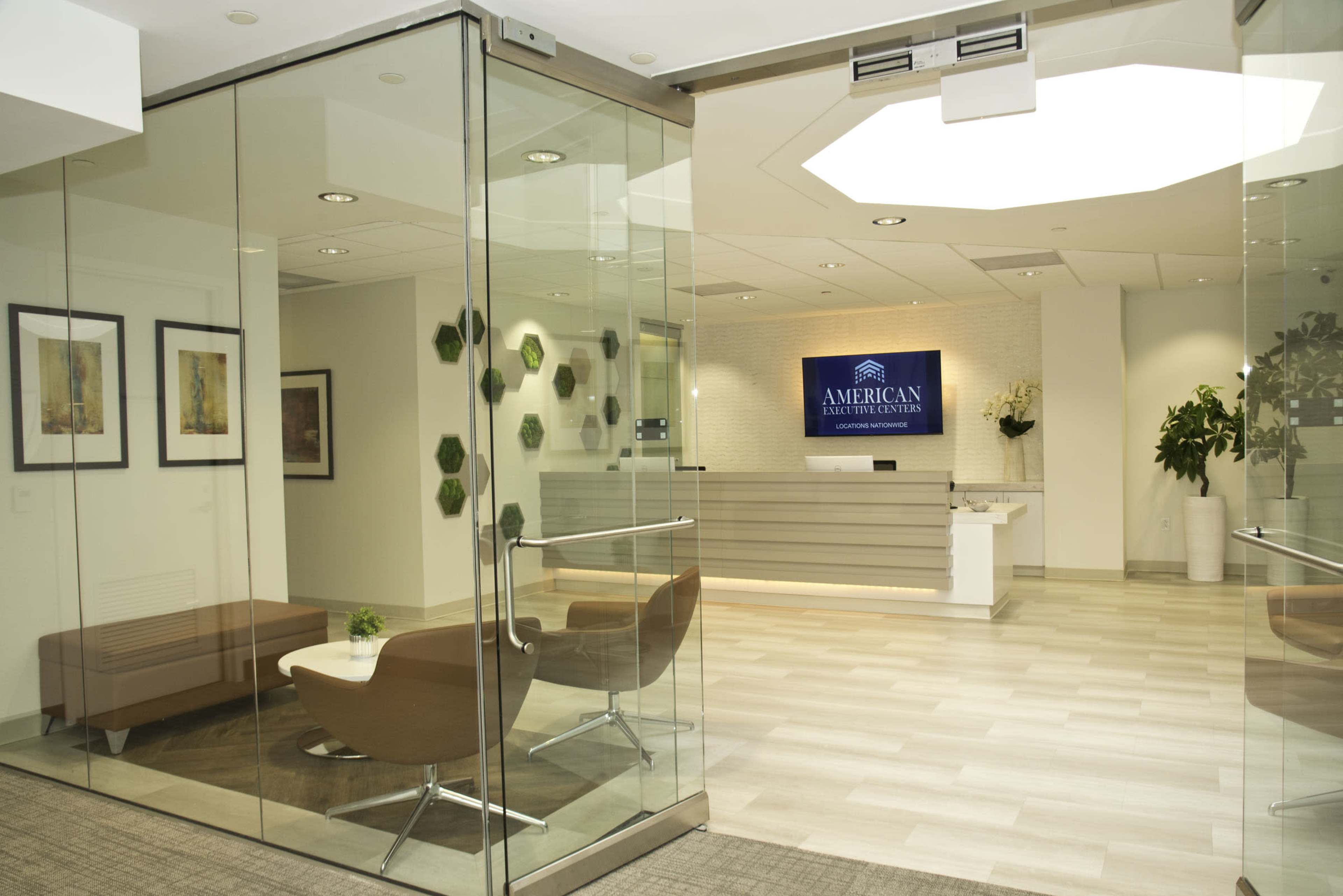 The image shows a modern reception area with glass walls, featuring a sign for "American Institute of Architects" and minimalist seating arrangements.