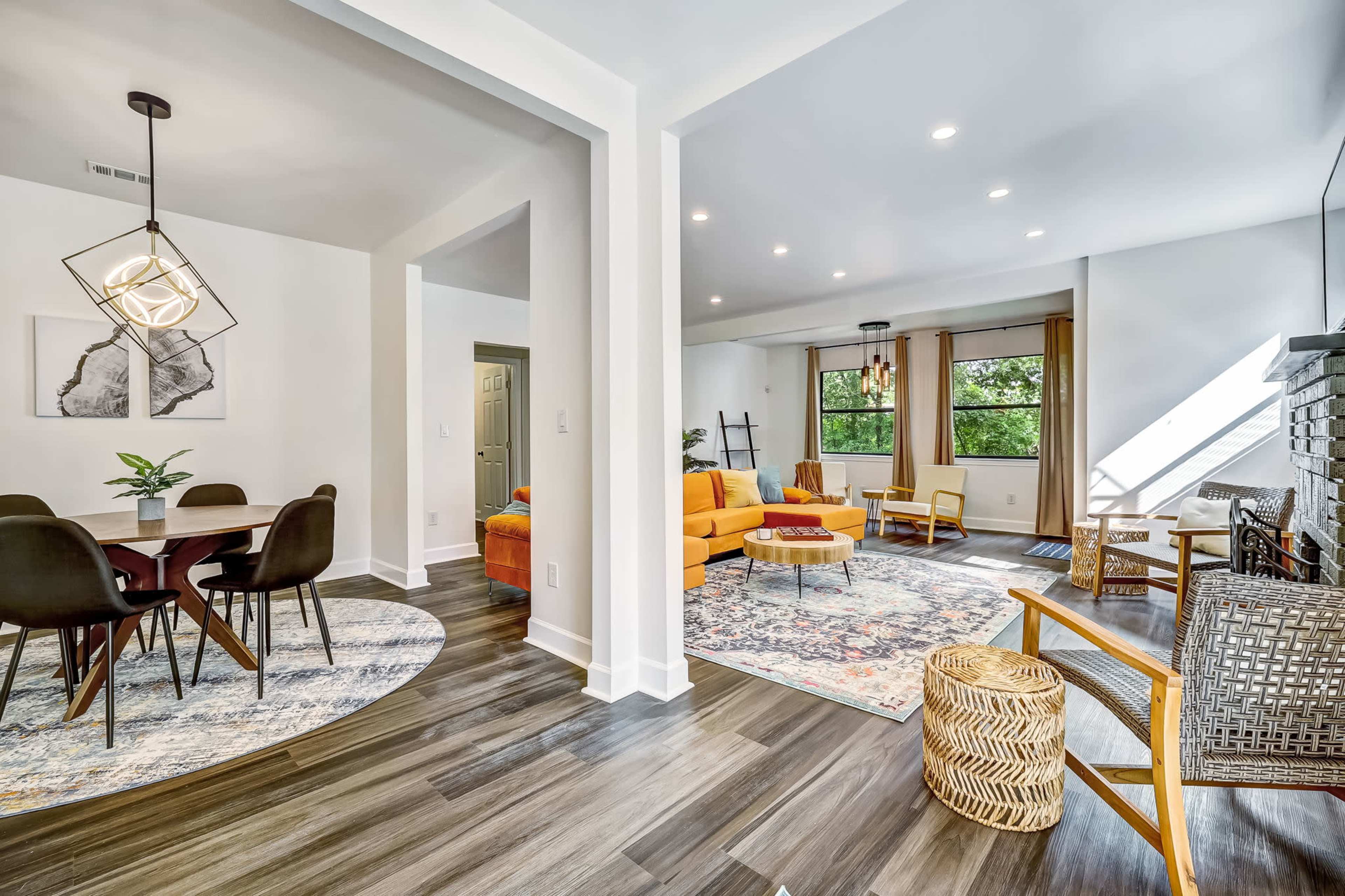 A modern living space featuring a yellow sofa, a dining area with a round table, and a mix of hardwood and area rugs.
