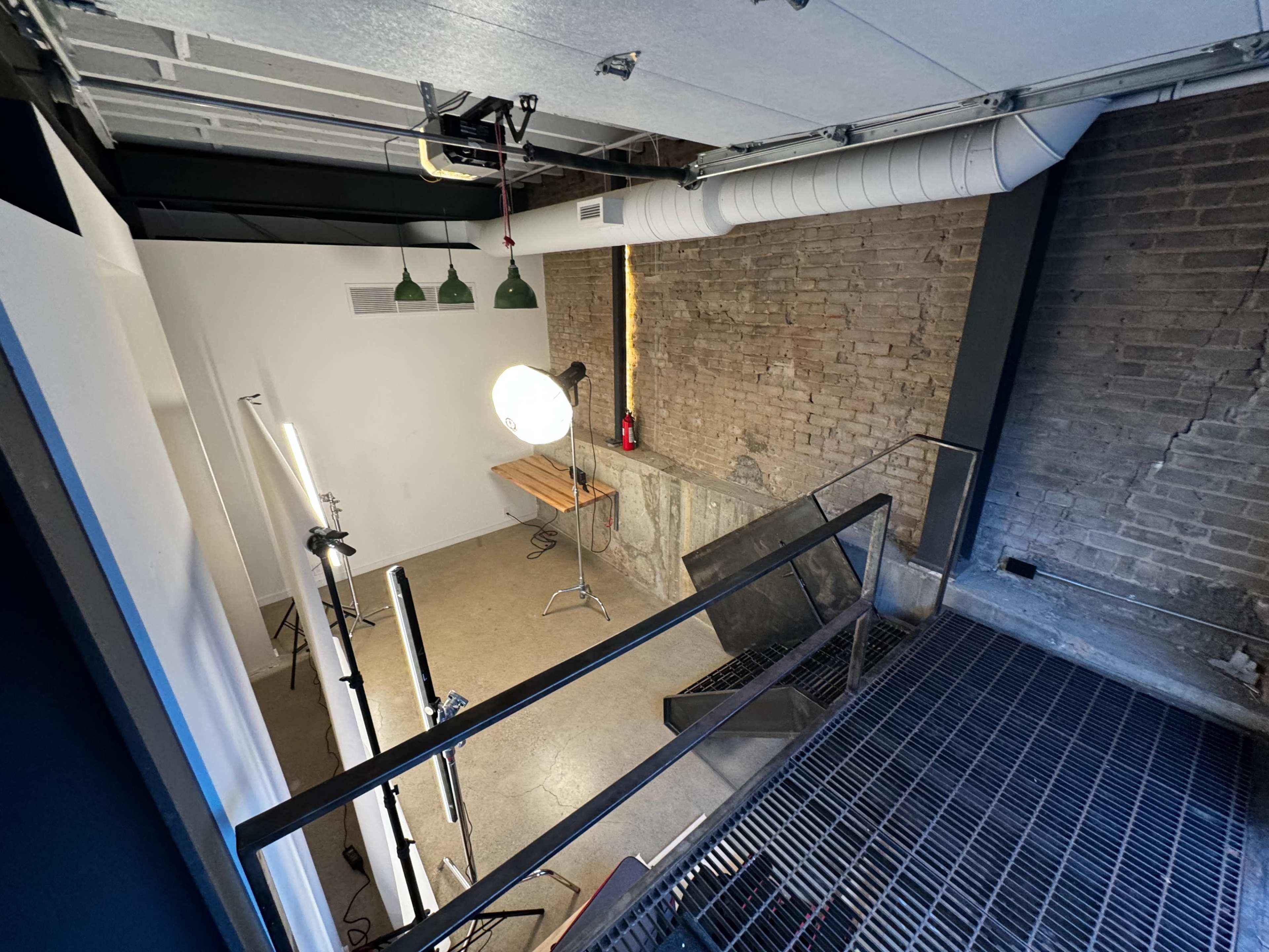 A studio space with a wooden table, lighting equipment, and exposed brick walls.