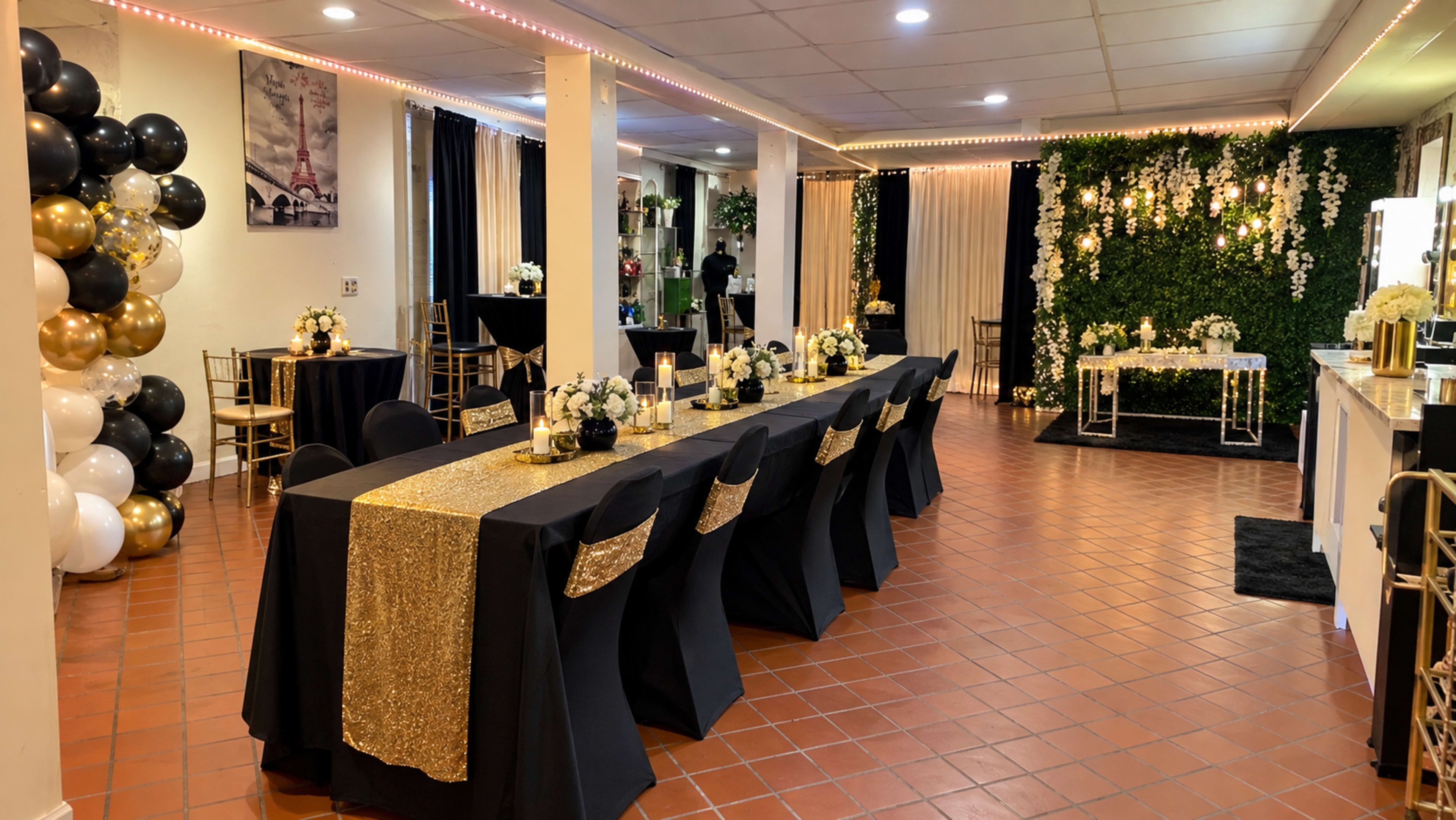 The image shows an elegantly decorated banquet hall featuring black and gold table settings, floral arrangements, and greenery on the walls.