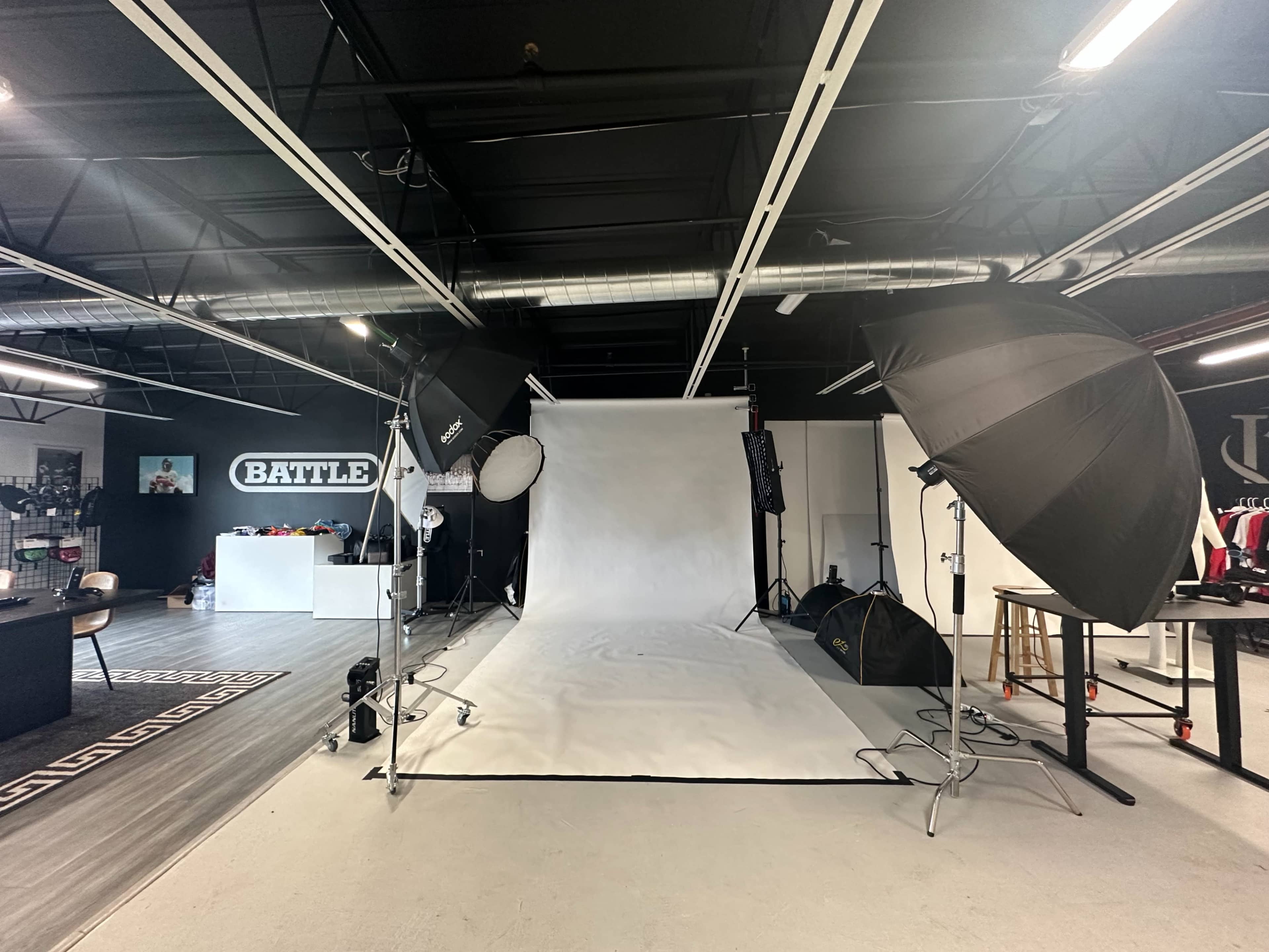 A photography studio with a white backdrop surrounded by lighting equipment and various studio props.