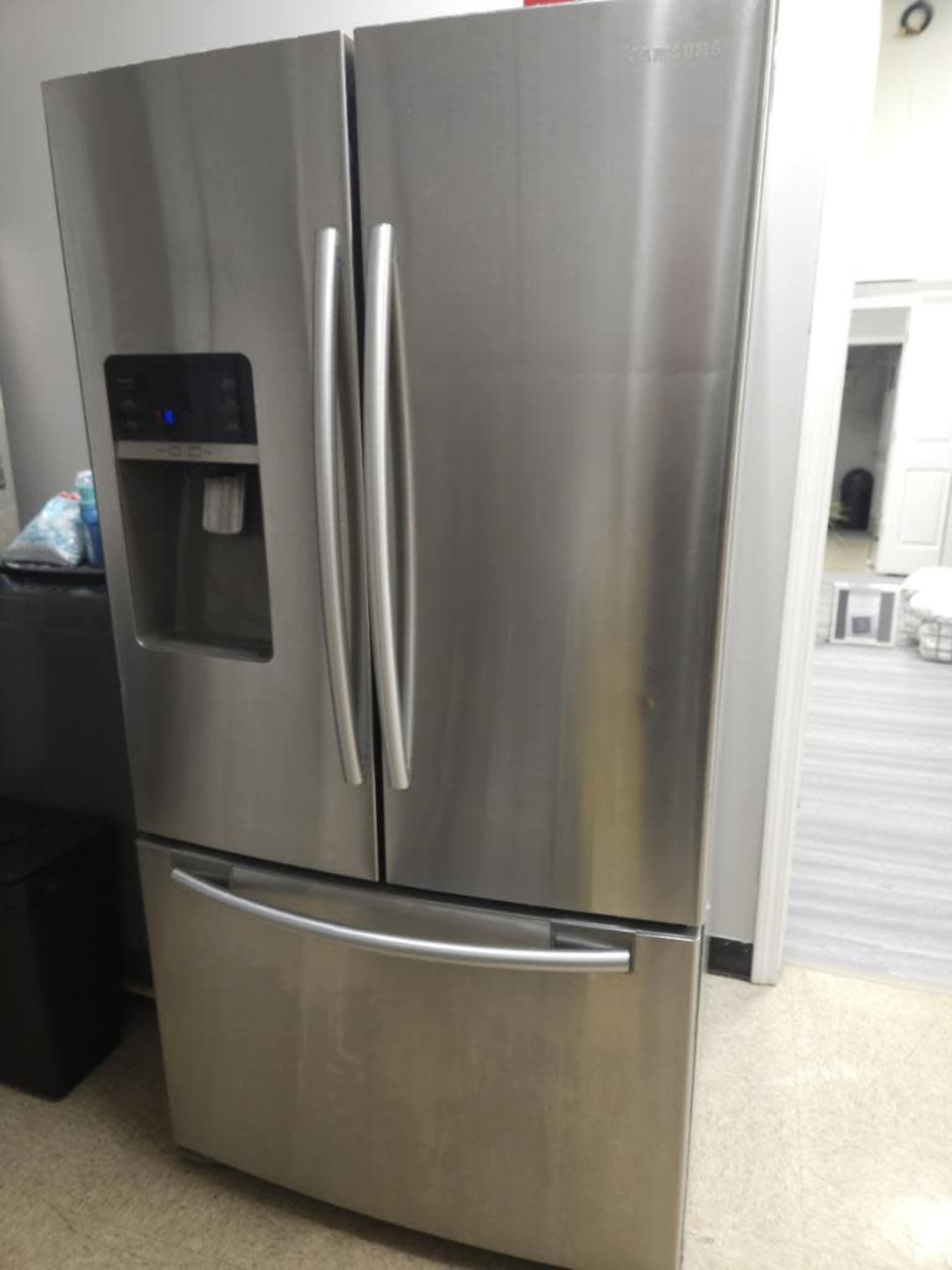 A stainless steel French door refrigerator is positioned in a kitchen setting.