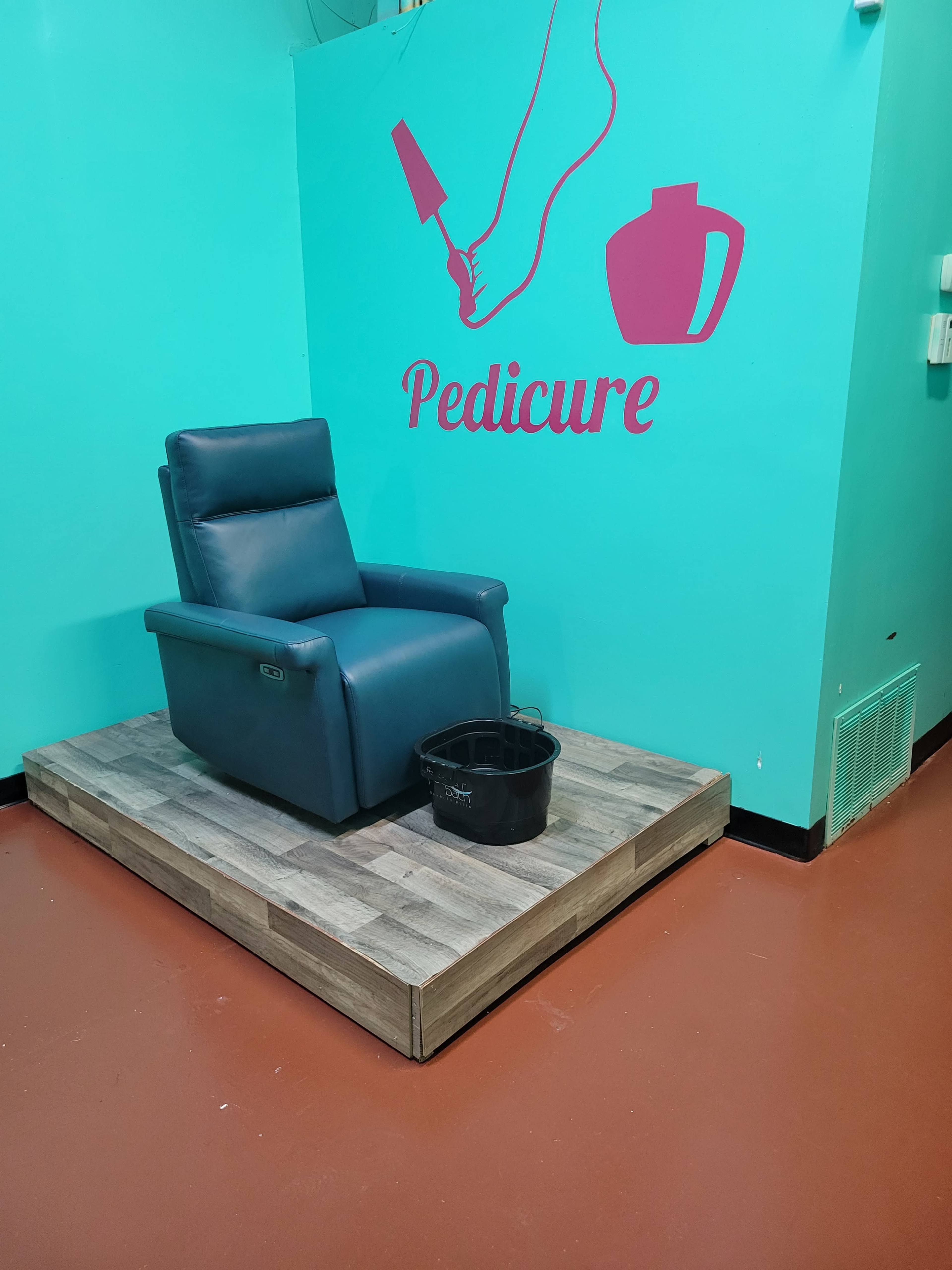 A blue pedicure chair positioned on a wooden platform against a turquoise wall with the word "Pedicure" displayed on it.