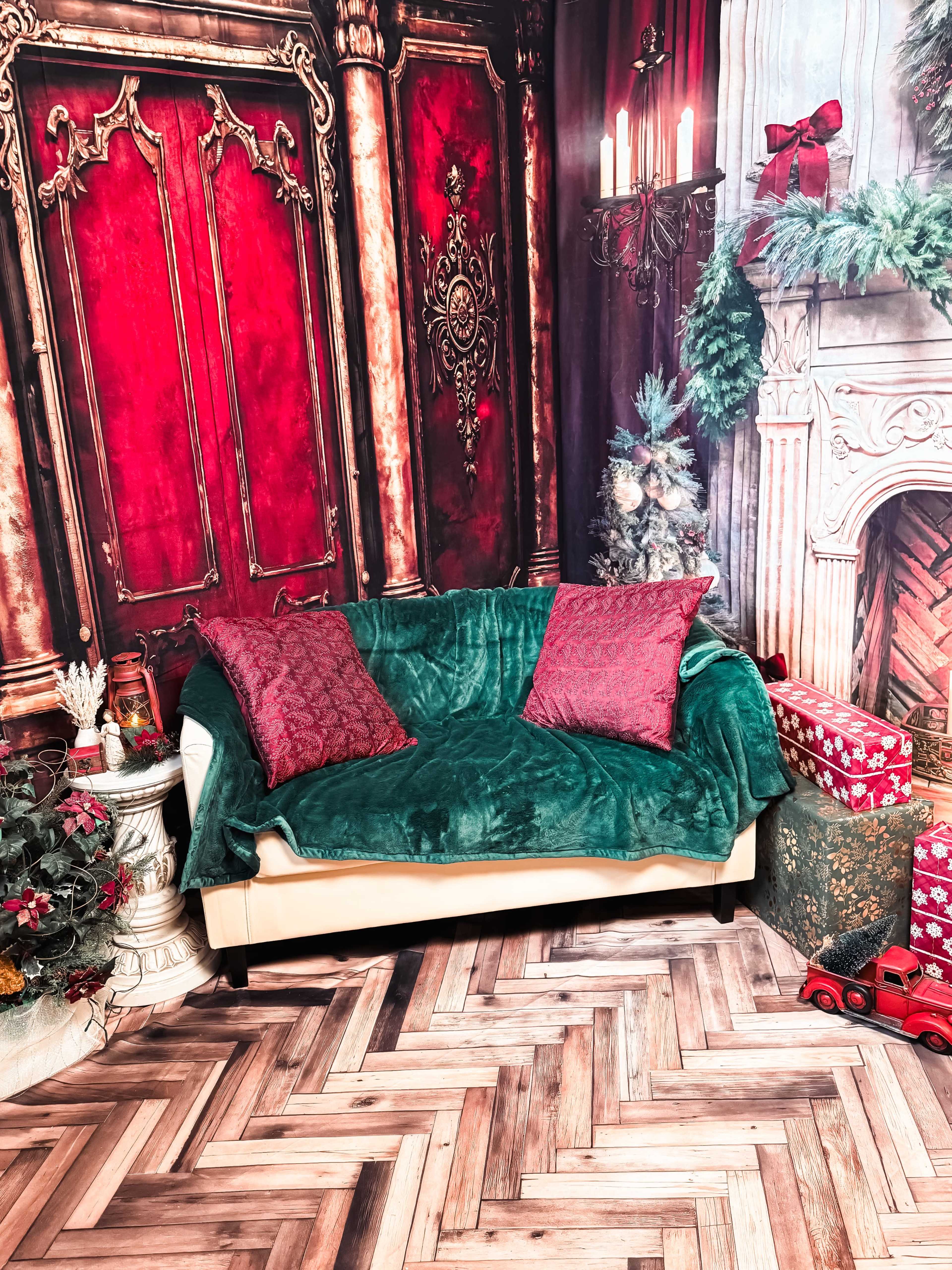 The scene features a decorated corner with a green couch draped with a plush throw, flanked by decorative pillows and surrounded by festive holiday decor, including wrapped gifts and a Christmas tree.