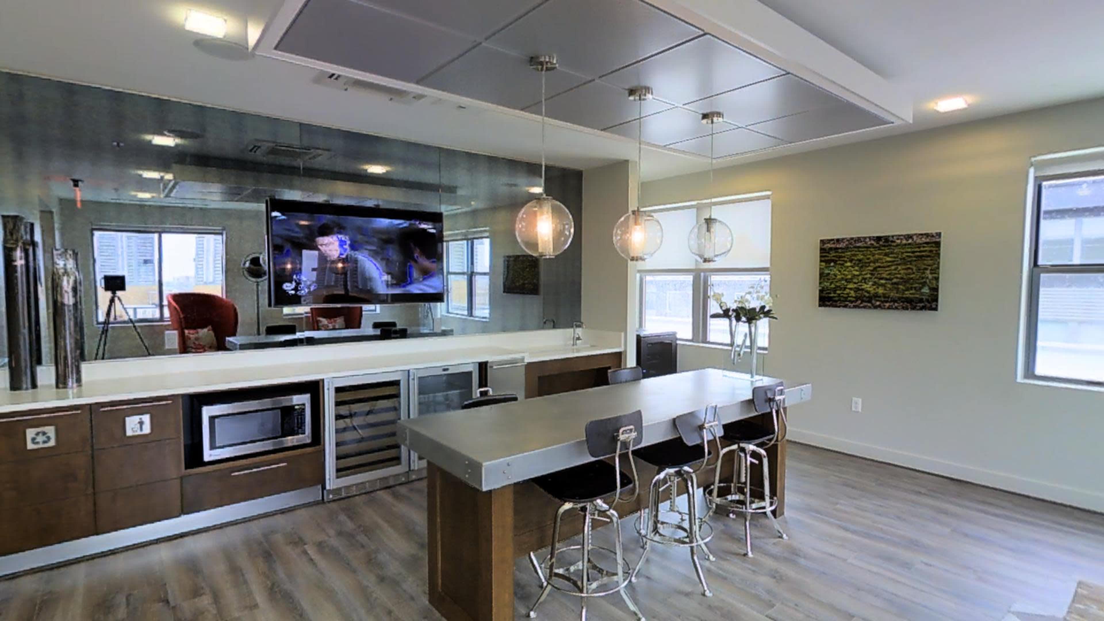 A modern kitchen with a large island, bar stools, and a television mounted on the wall.
