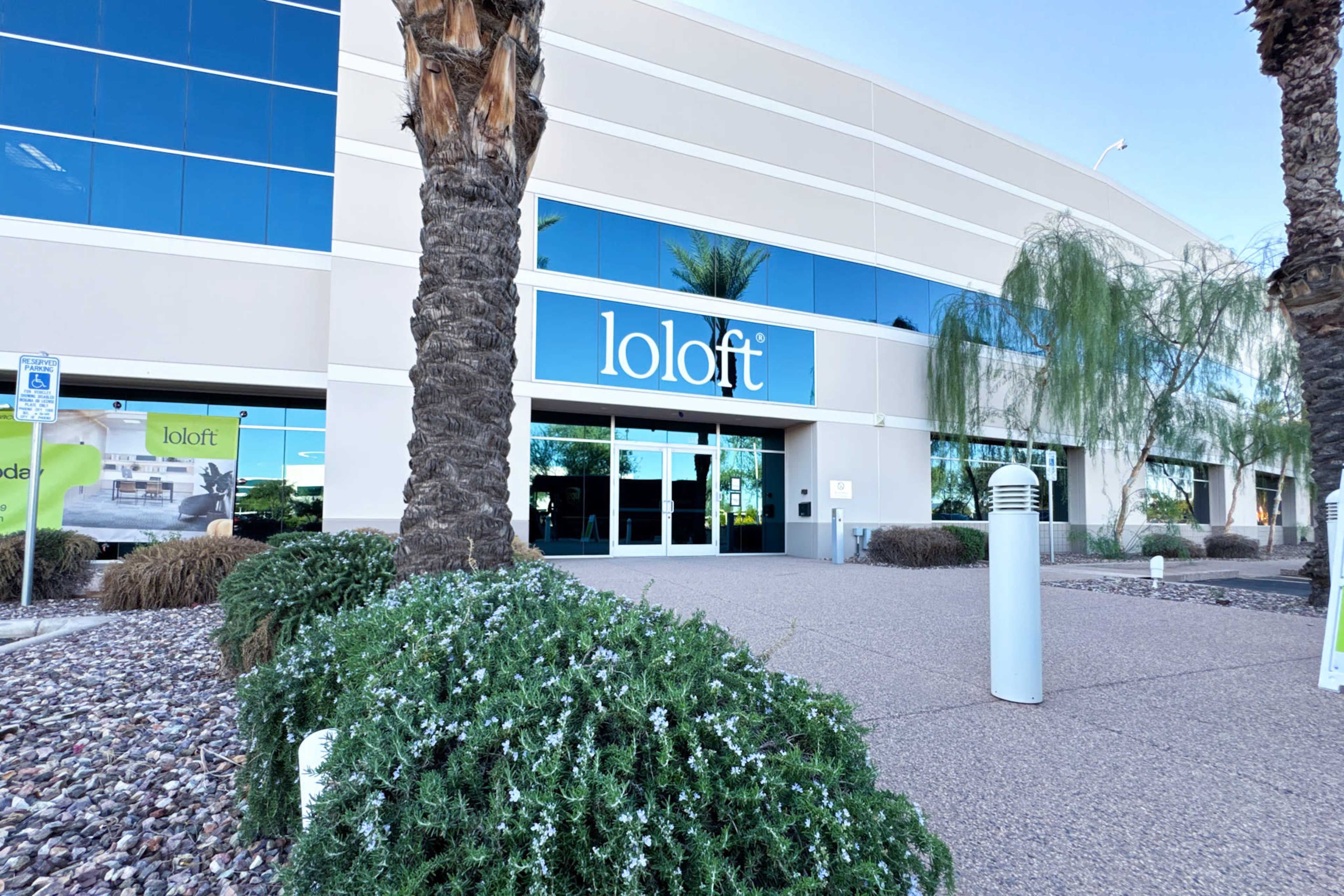 The image shows the entrance of a modern building with large windows and the name "loloft" prominently displayed.