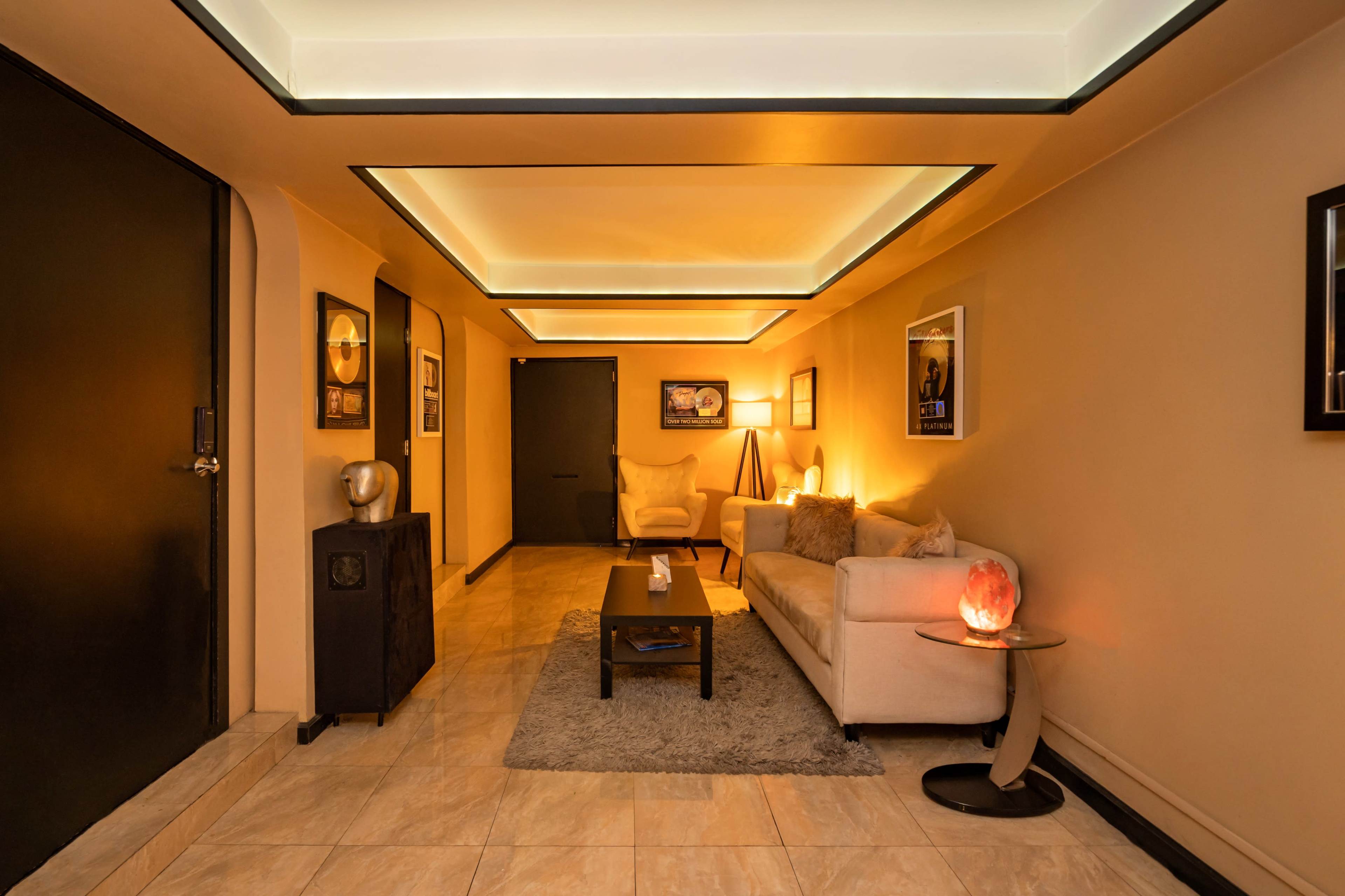 A modern living room features a beige sofa, a small coffee table, and soft lighting under a tray ceiling.