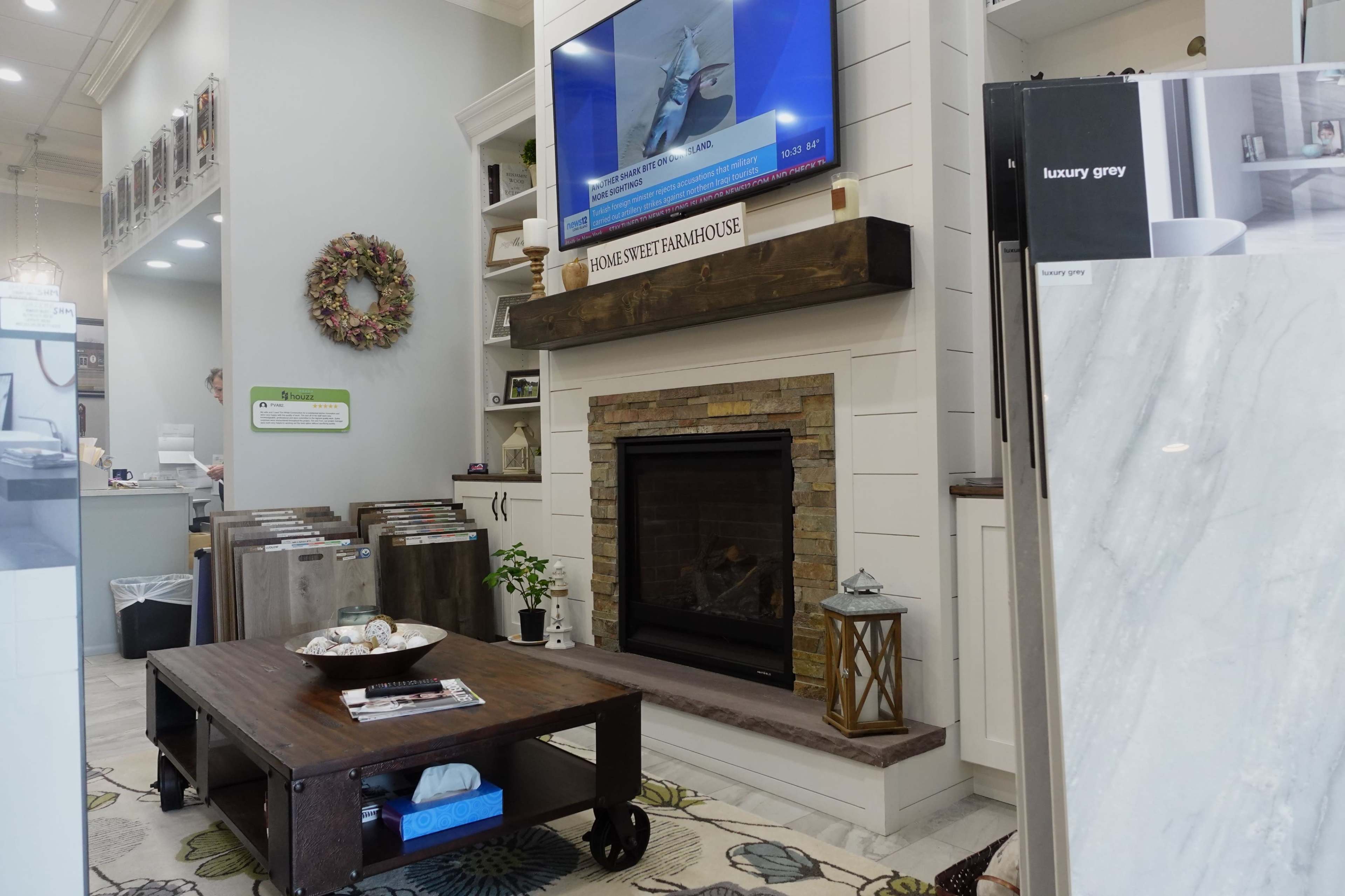 A cozy interior of a design showroom featuring a fireplace, a television above it, and various samples of flooring displayed.