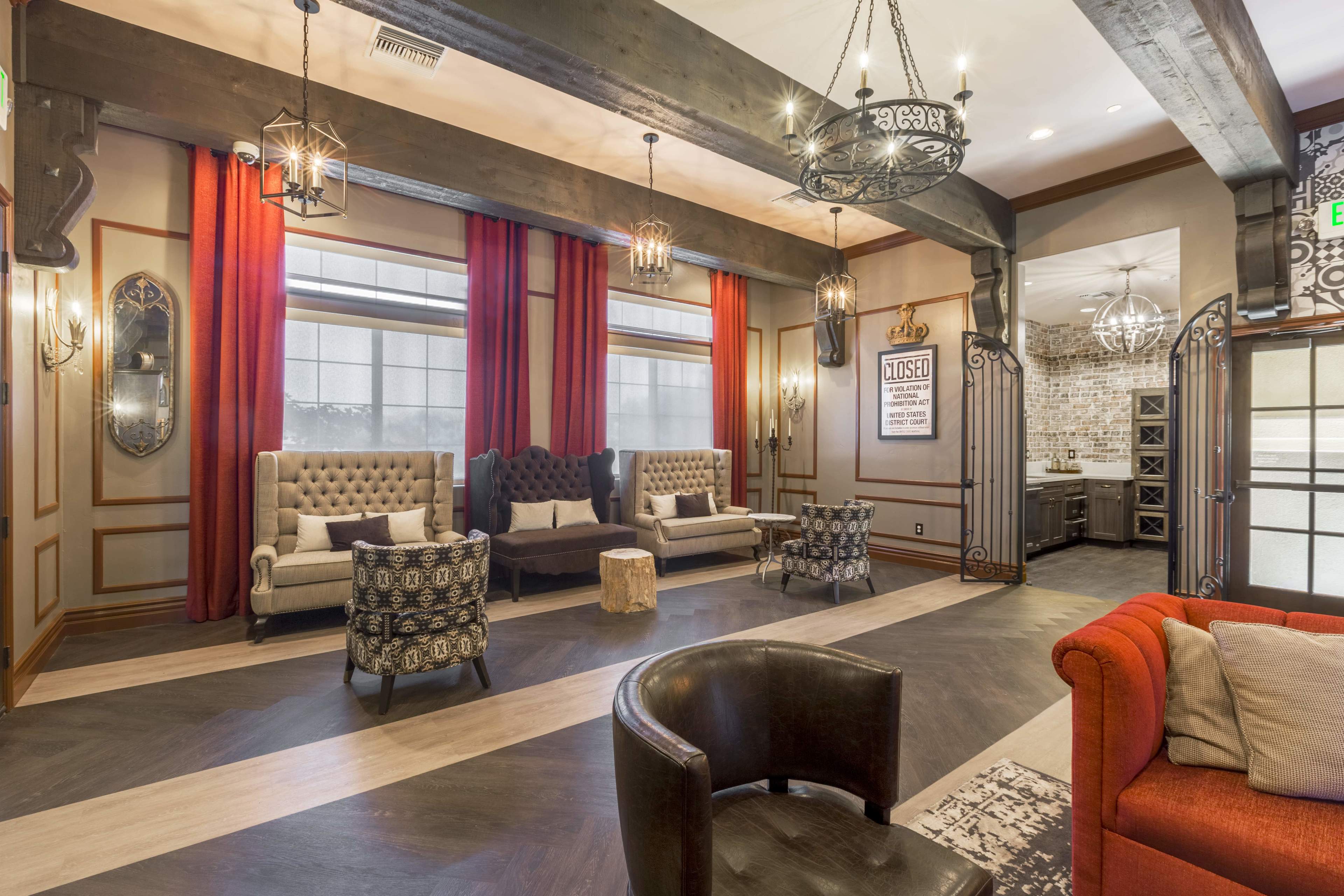 The scene features a stylish lounge area with tufted armchairs, a modern sofa, warm lighting fixtures, and wooden beams on the ceiling.