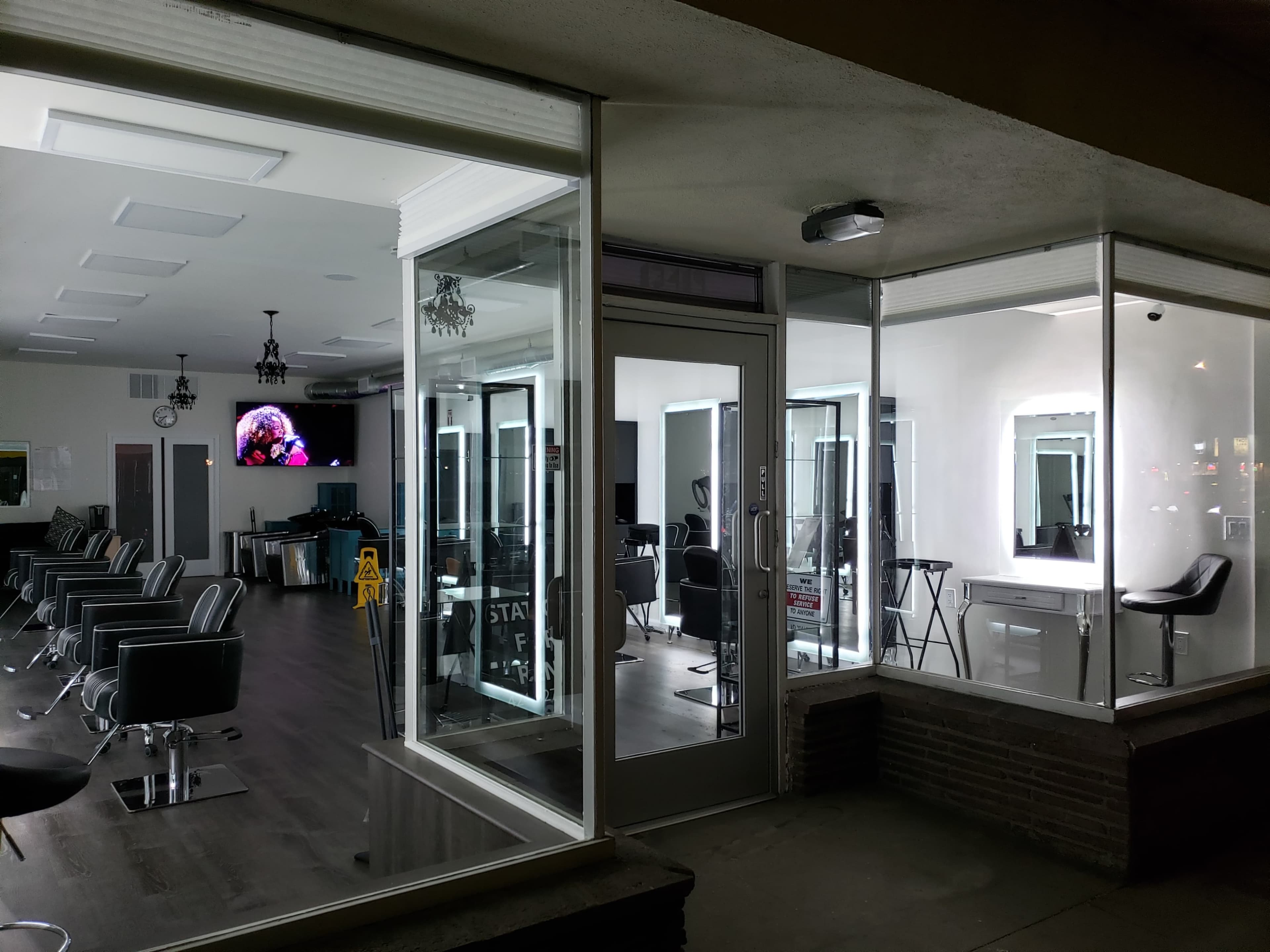 A well-lit hair salon with large windows, showcasing salon chairs and workstations inside.