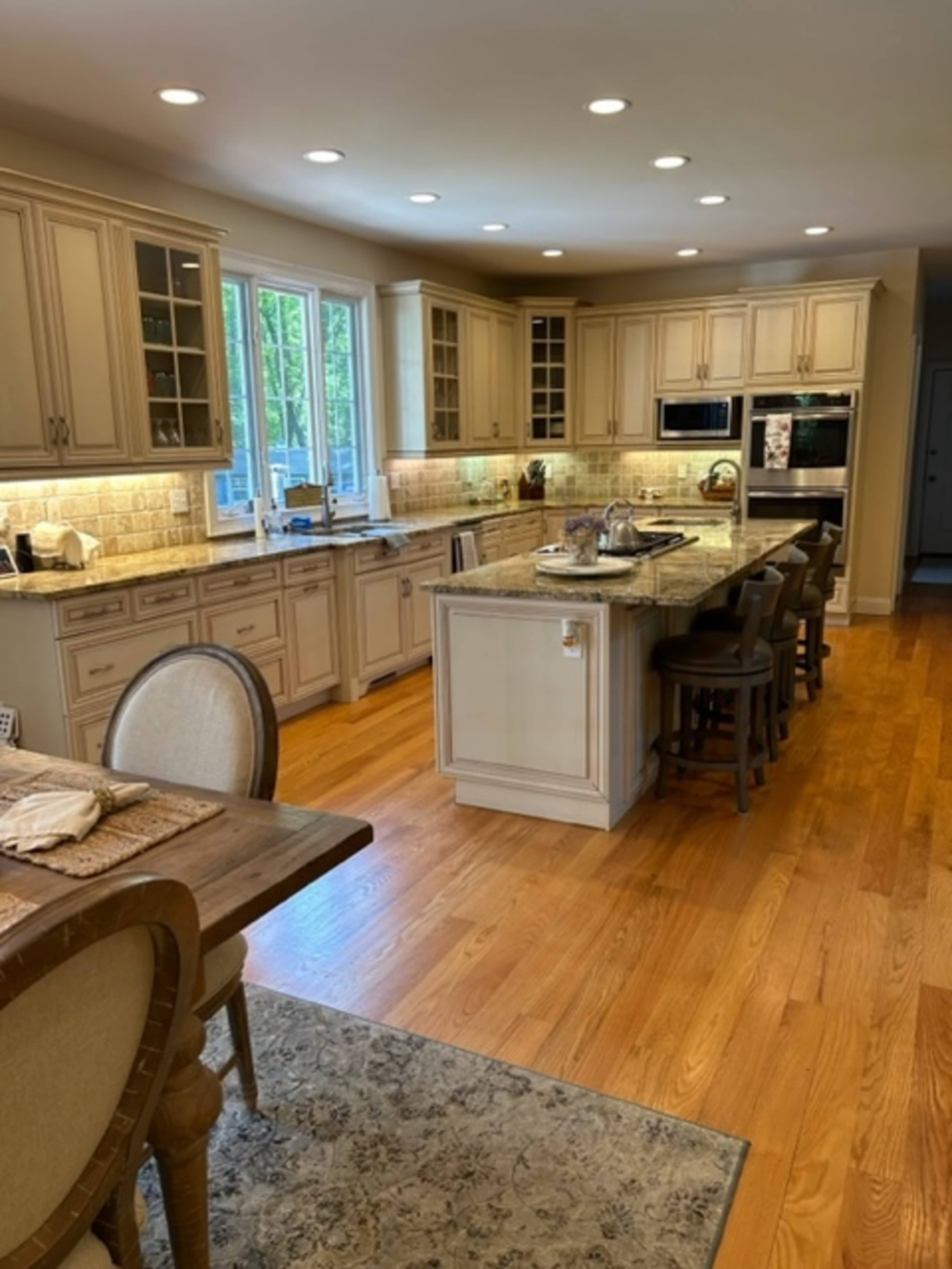 A spacious kitchen with wooden cabinets, granite countertops, and a large center island, illuminated by recessed lighting.