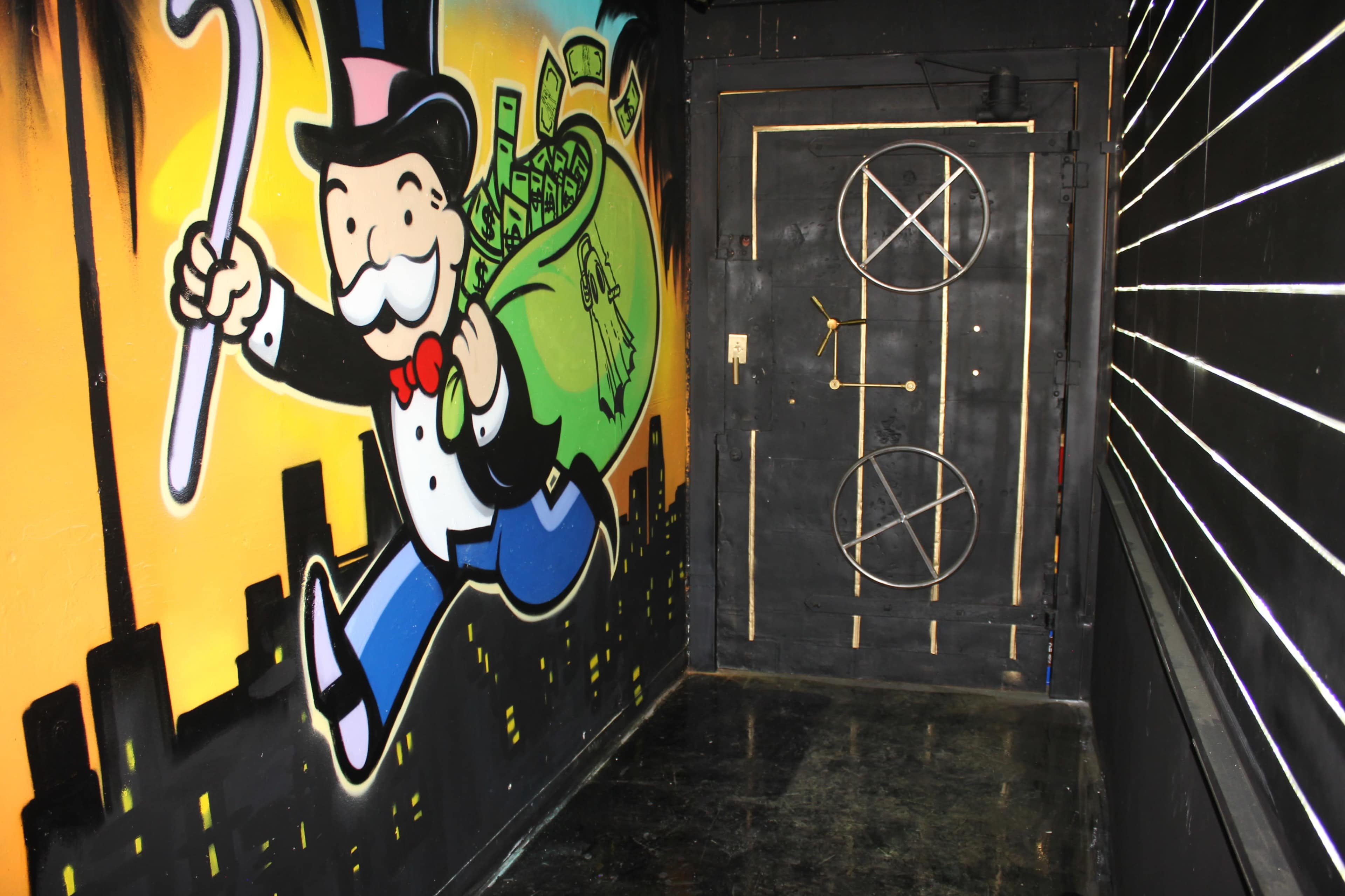 A vibrant mural of a man in a top hat carrying a bag of money next to a door featuring a circular design and a pentagram.