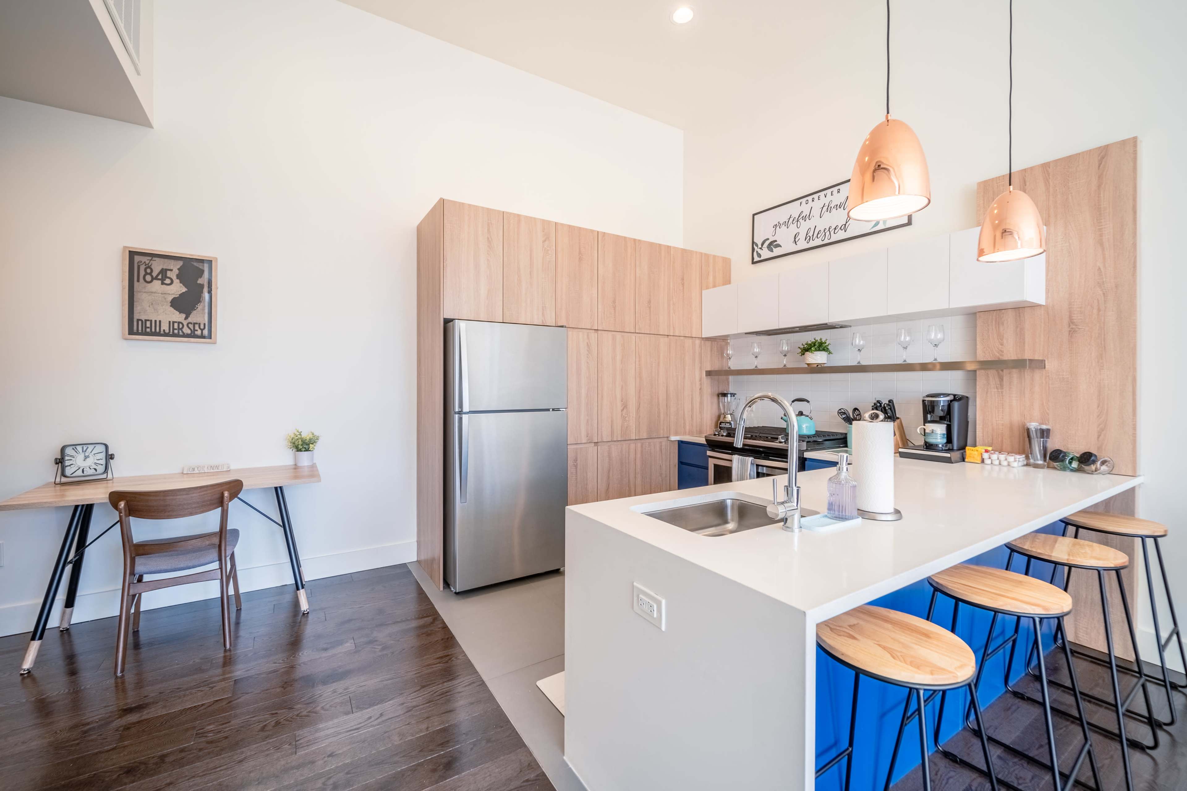 A modern kitchen featuring stainless steel appliances, blue cabinetry, and a large island with seating.