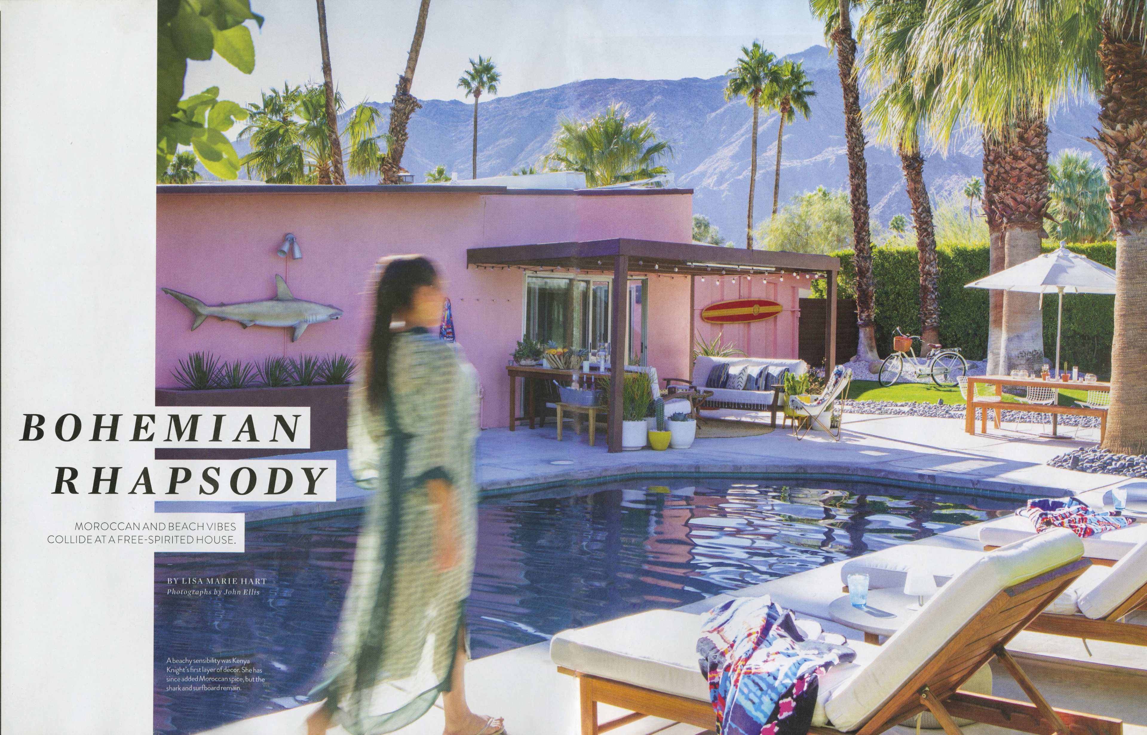 A vibrant poolside scene with palm trees, a pink house, and sun loungers, set against a backdrop of mountains.