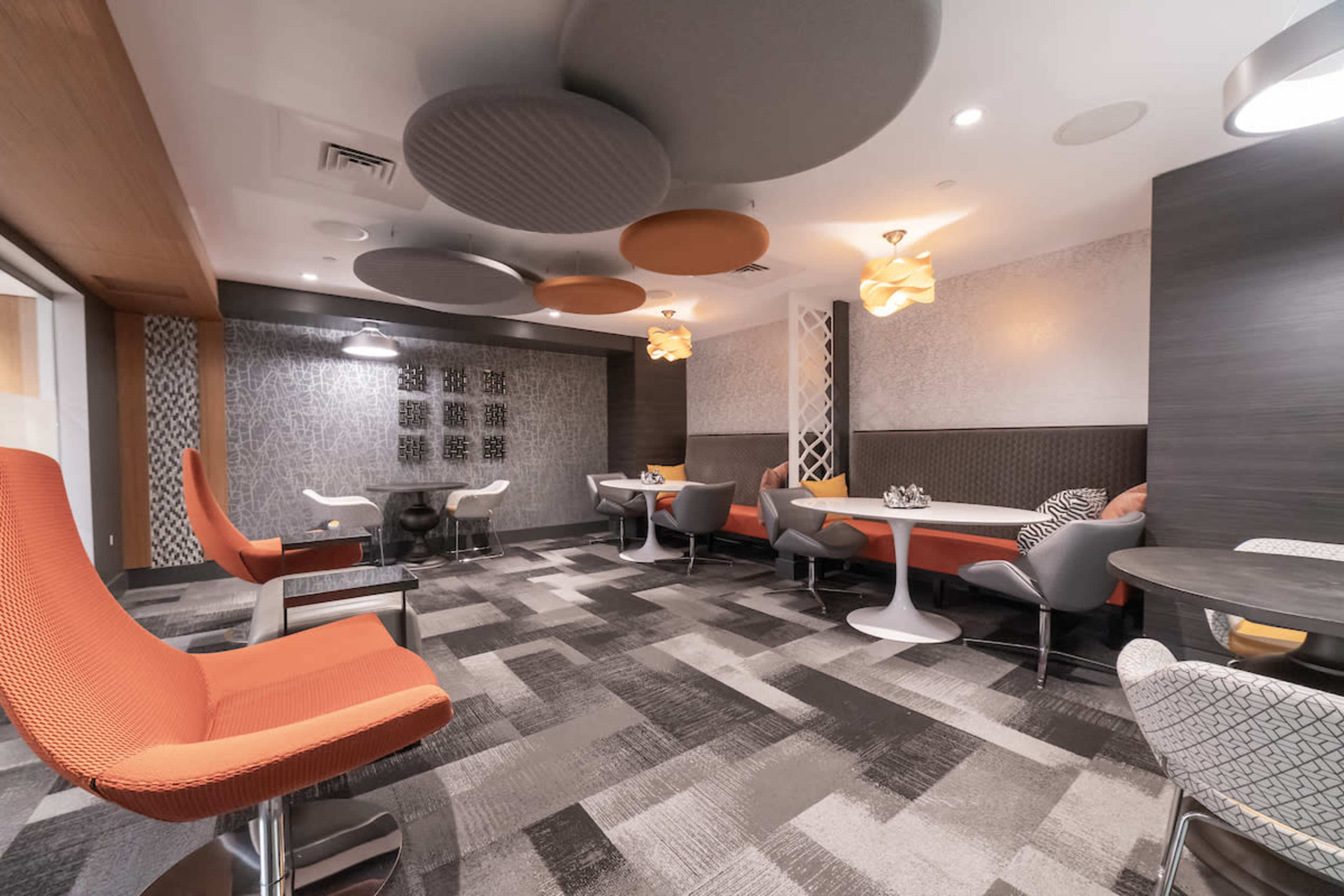 A modern interior space features a mix of seating options, textured walls, and unique ceiling panels in a lounge area.