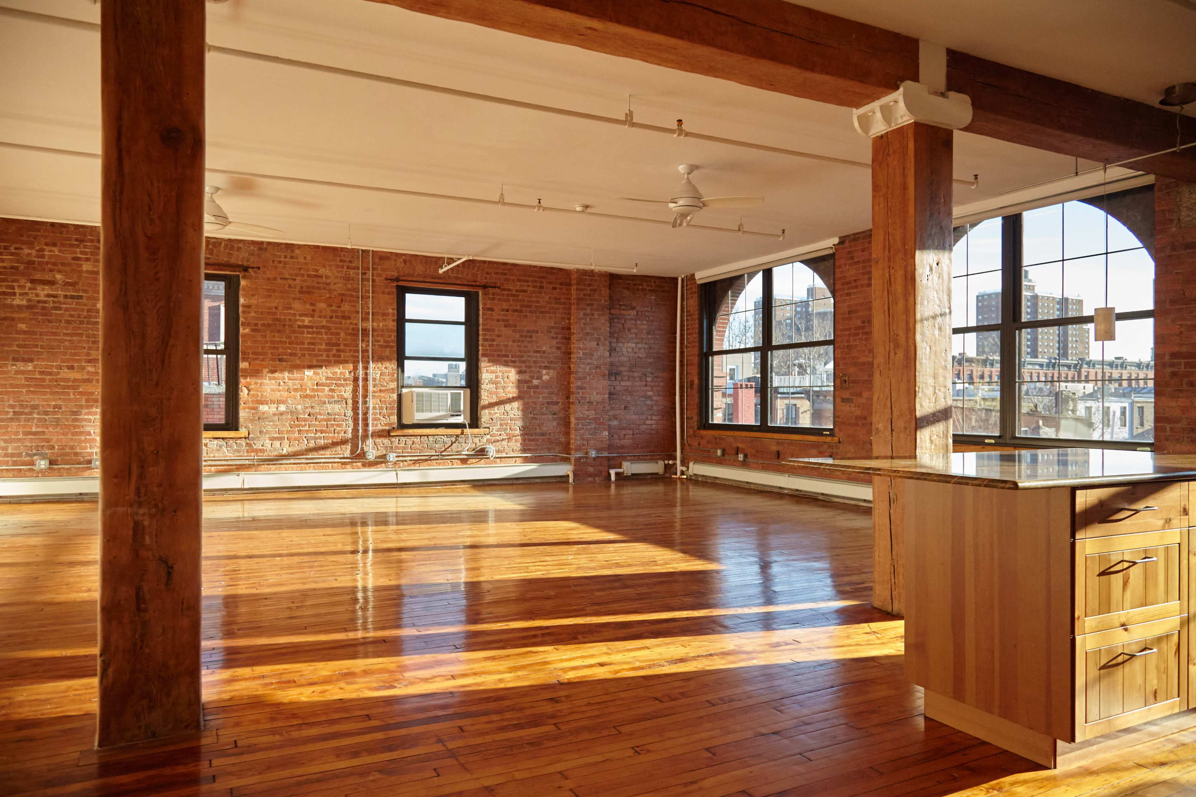A spacious loft with wooden floors, exposed brick walls, and large windows providing natural light.
