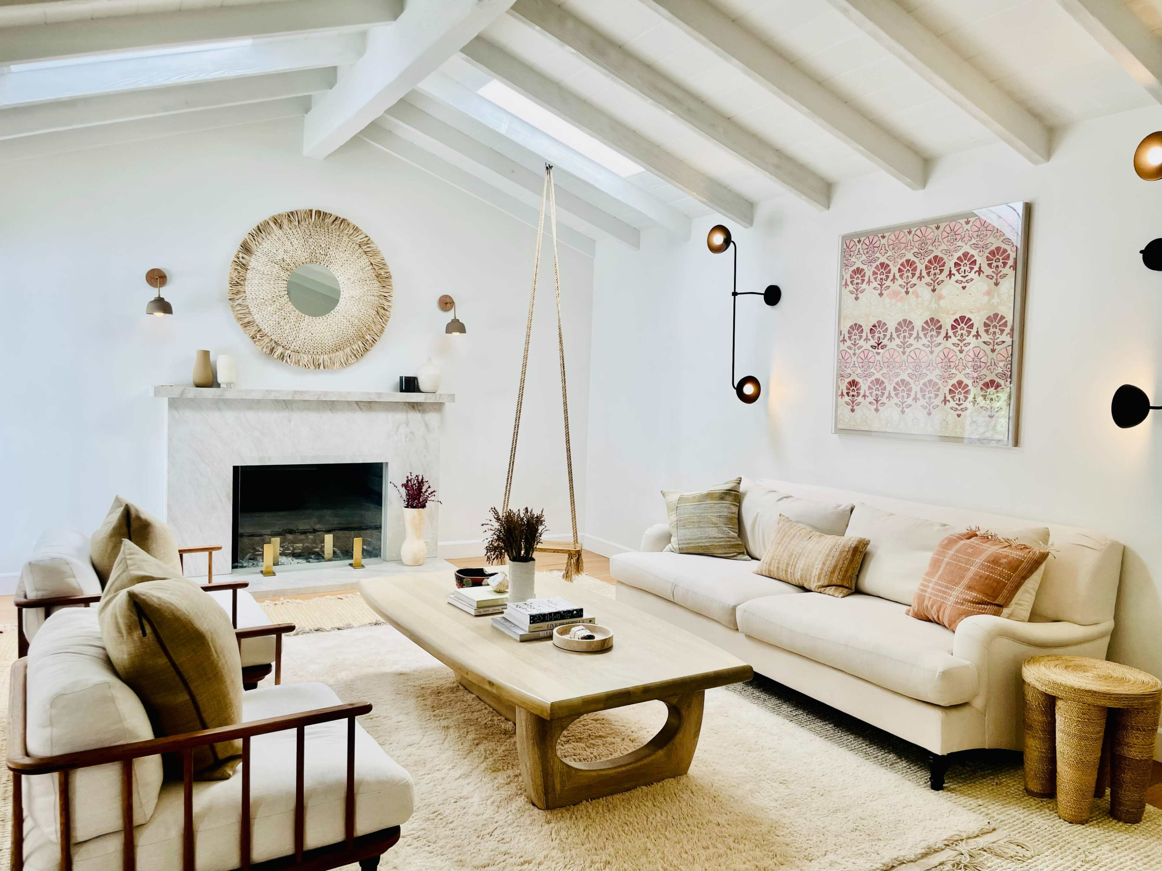 The living room features a white sofa, wooden chairs, a large coffee table, and a fireplace, all complemented by a decorative wall mirror and artwork.