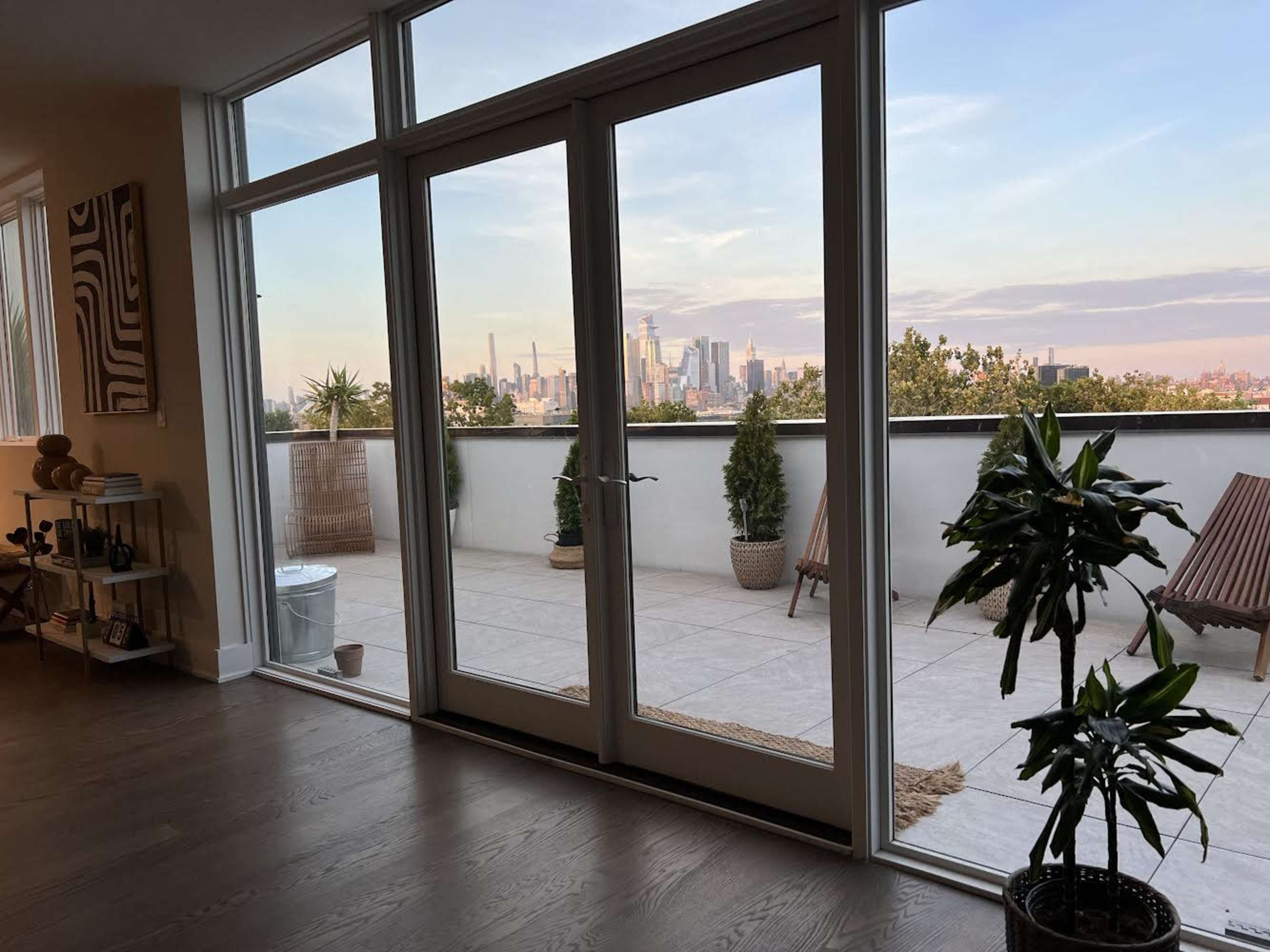 A modern indoor space with large sliding glass doors leading to a balcony that overlooks a city skyline.