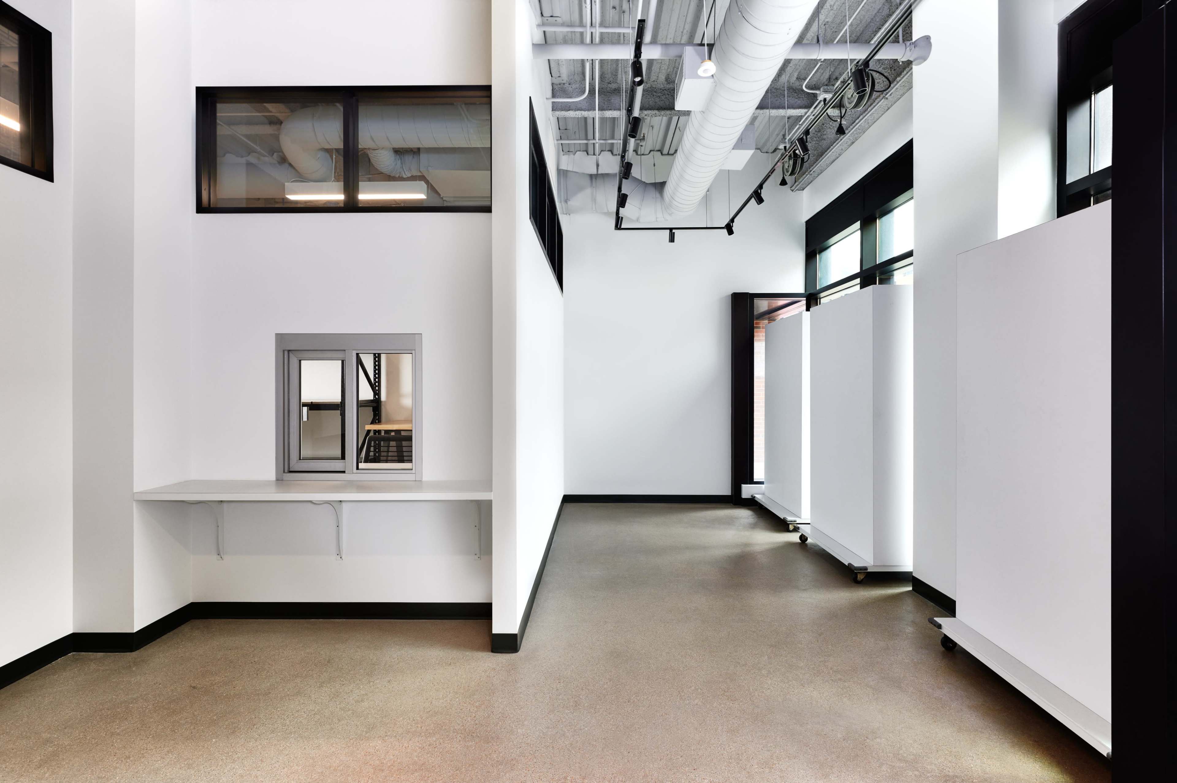 A spacious, modern interior with white walls, large windows, and a clean, uncluttered floor layout.
