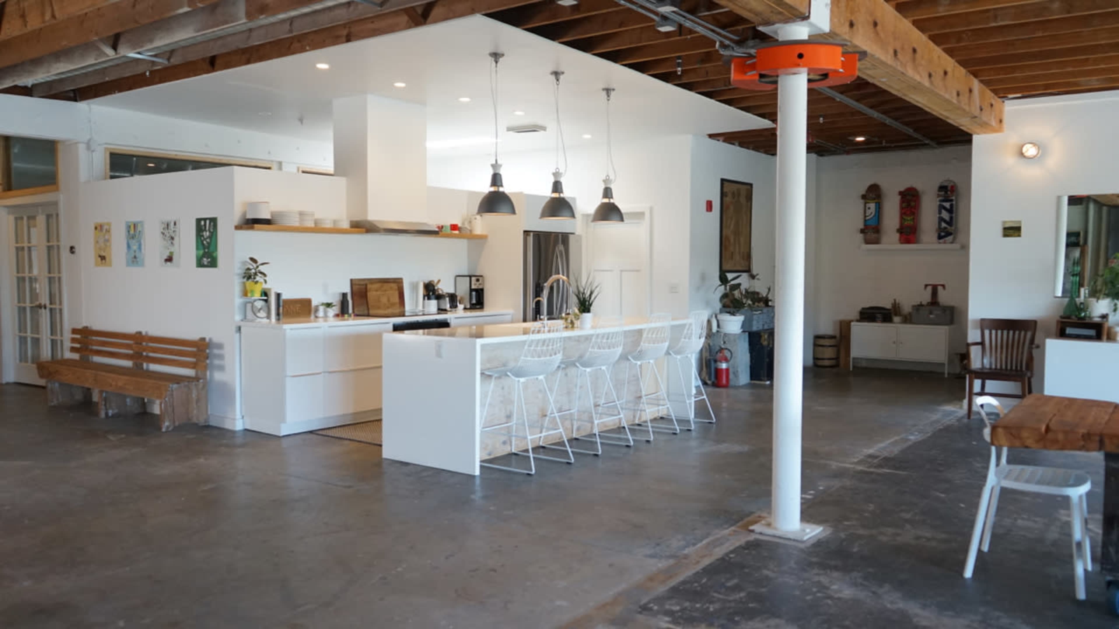 A spacious, modern kitchen with white cabinetry, bar stools, and an open dining area.