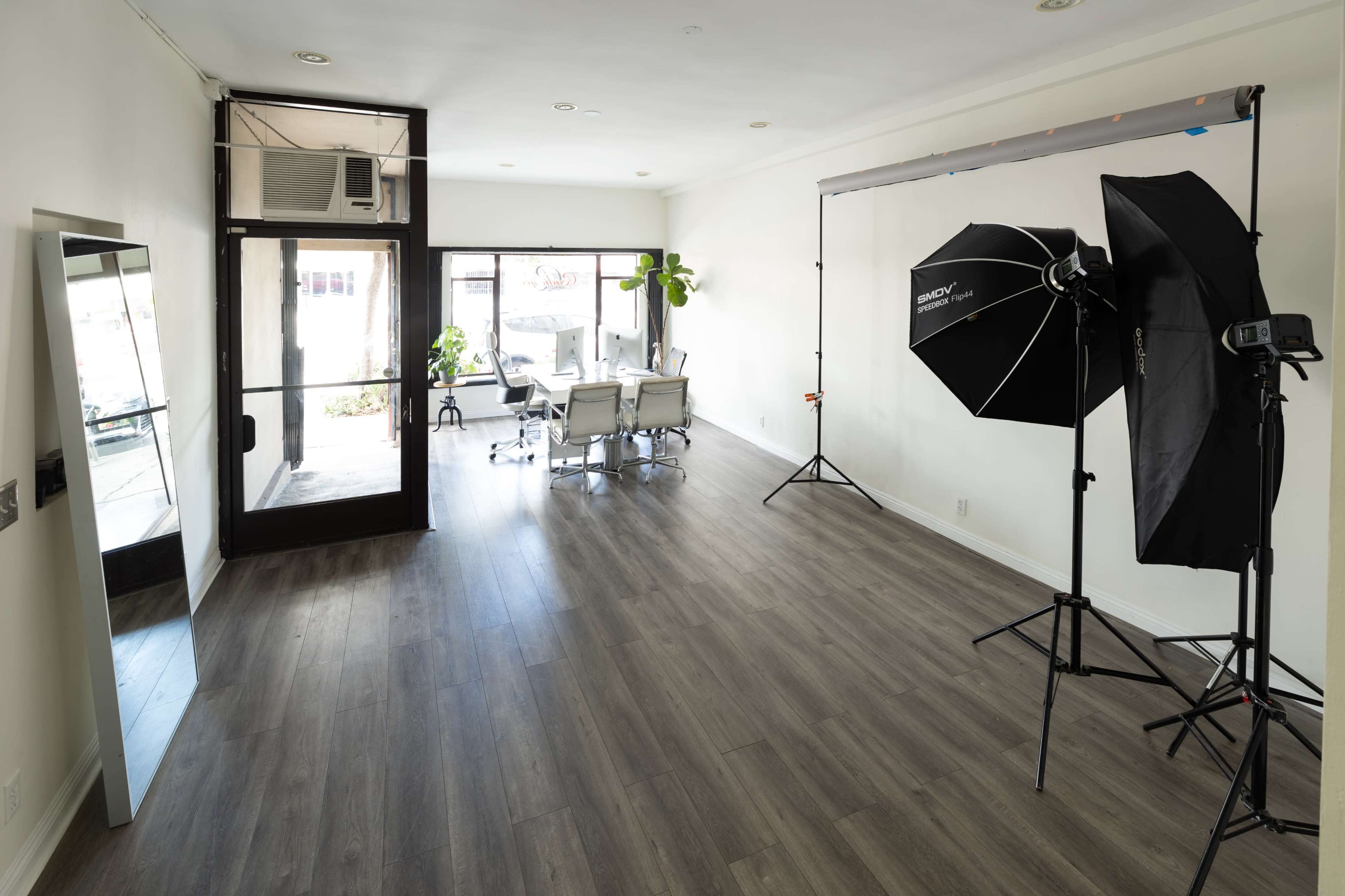 A spacious, well-lit room with a conference table and chairs, along with photography equipment set up near large windows.
