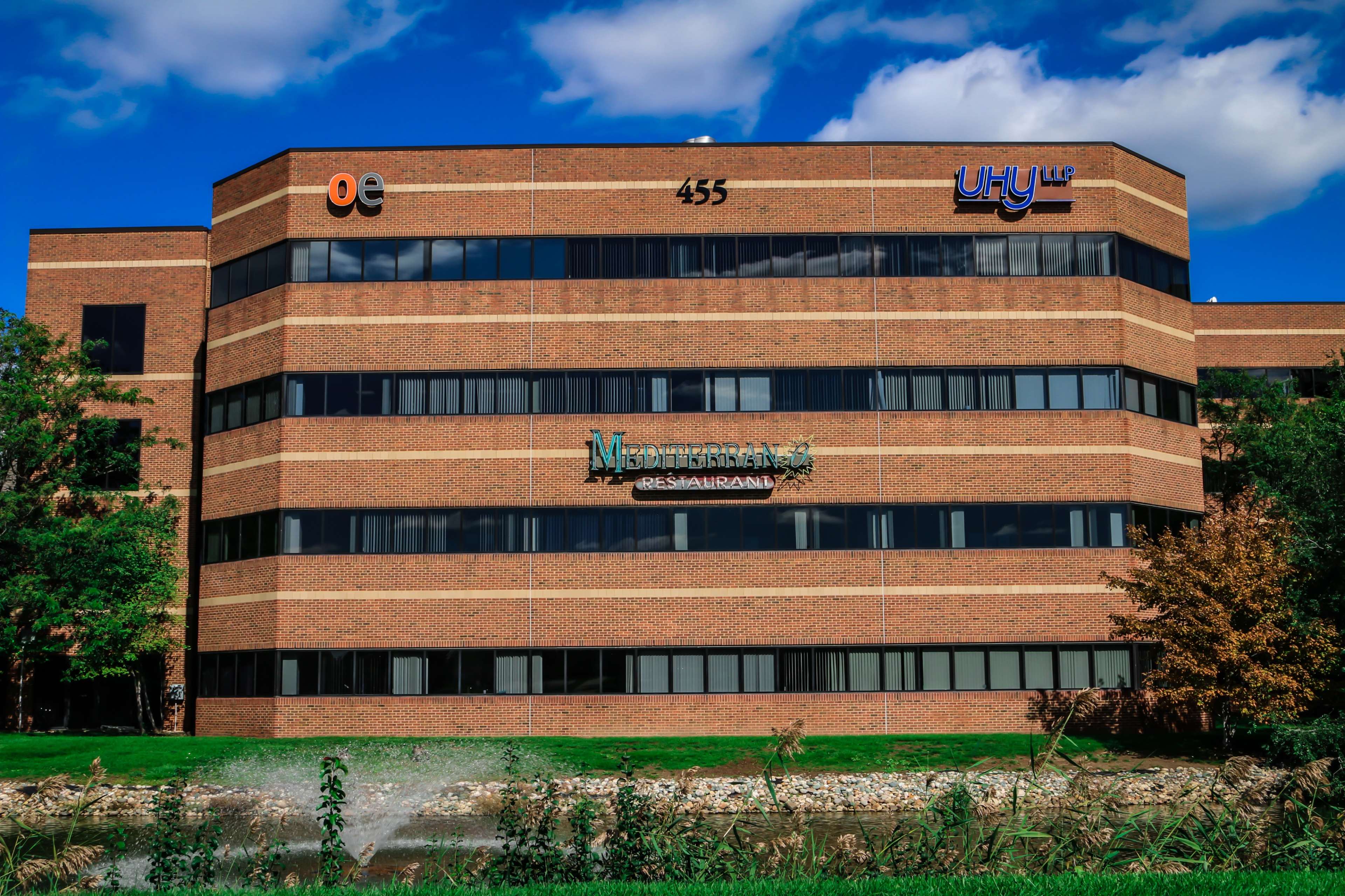 A three-story brick office building with signage indicating various businesses, including "OE," "UHY LLC," and "Mediavine."
