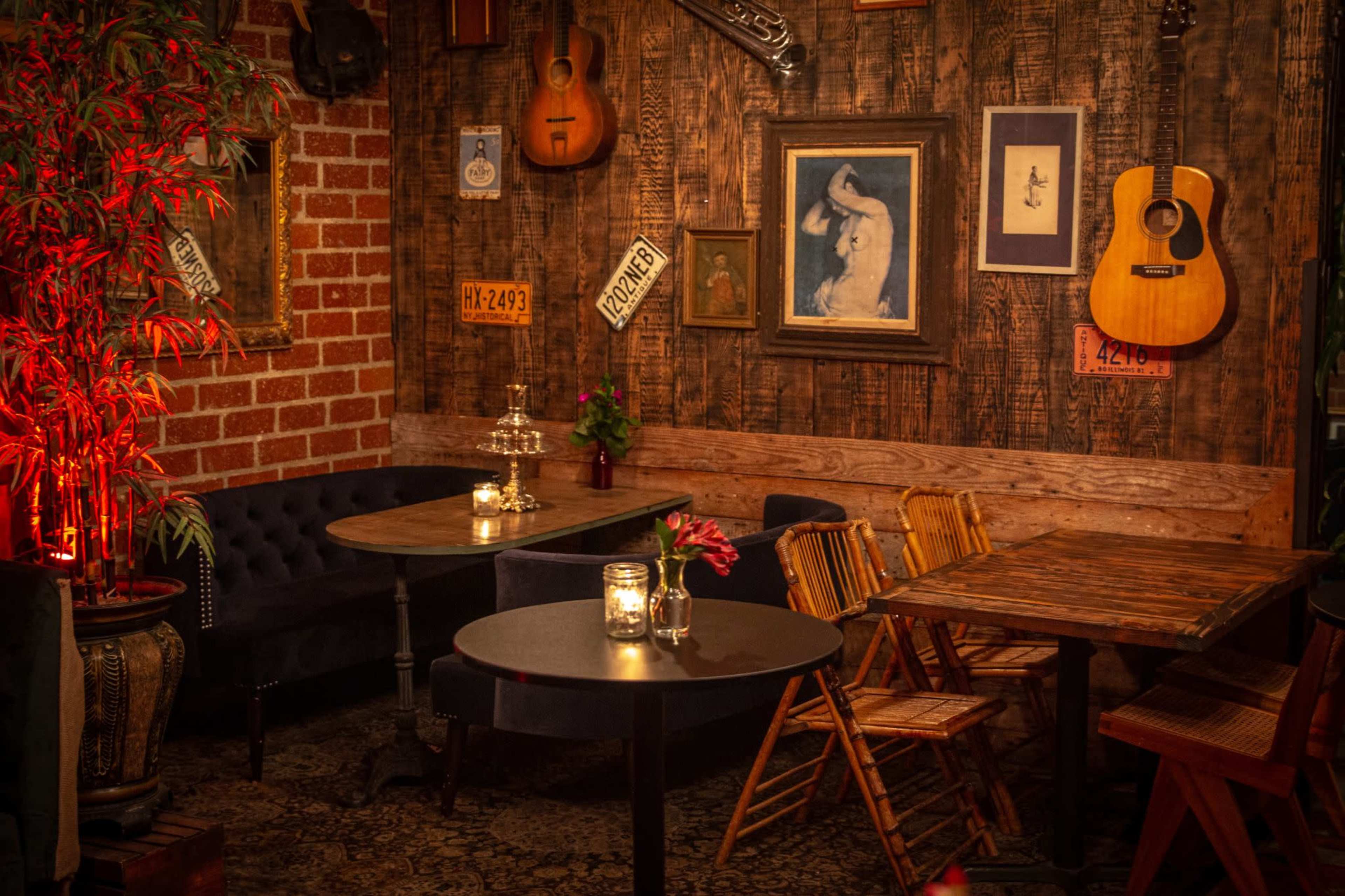 The image depicts a cozy cafe setting with wooden walls adorned with musical instruments and artwork, illuminated by warm light from candles on the tables.