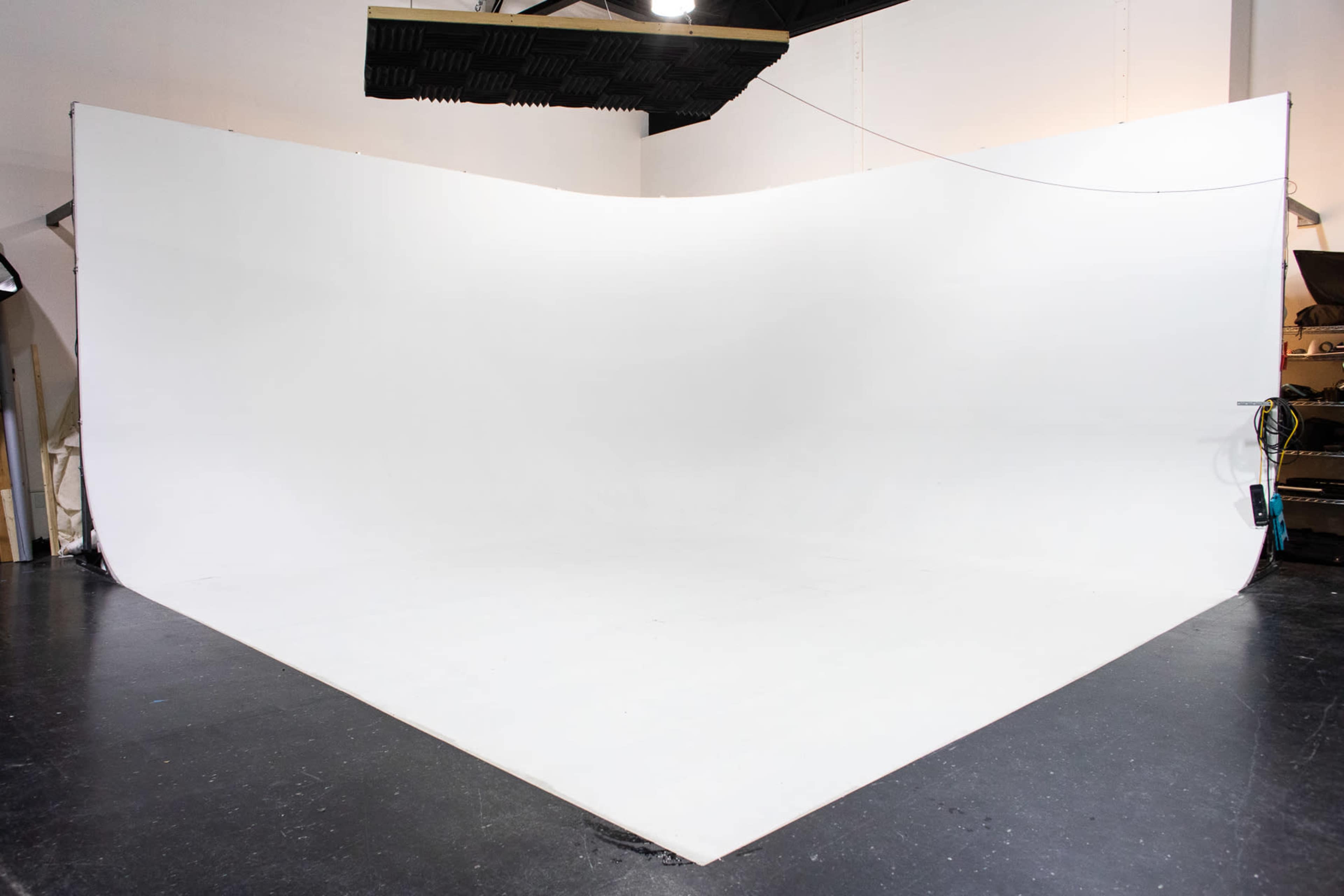 A large, empty studio space with a curved white backdrop and a dark floor.