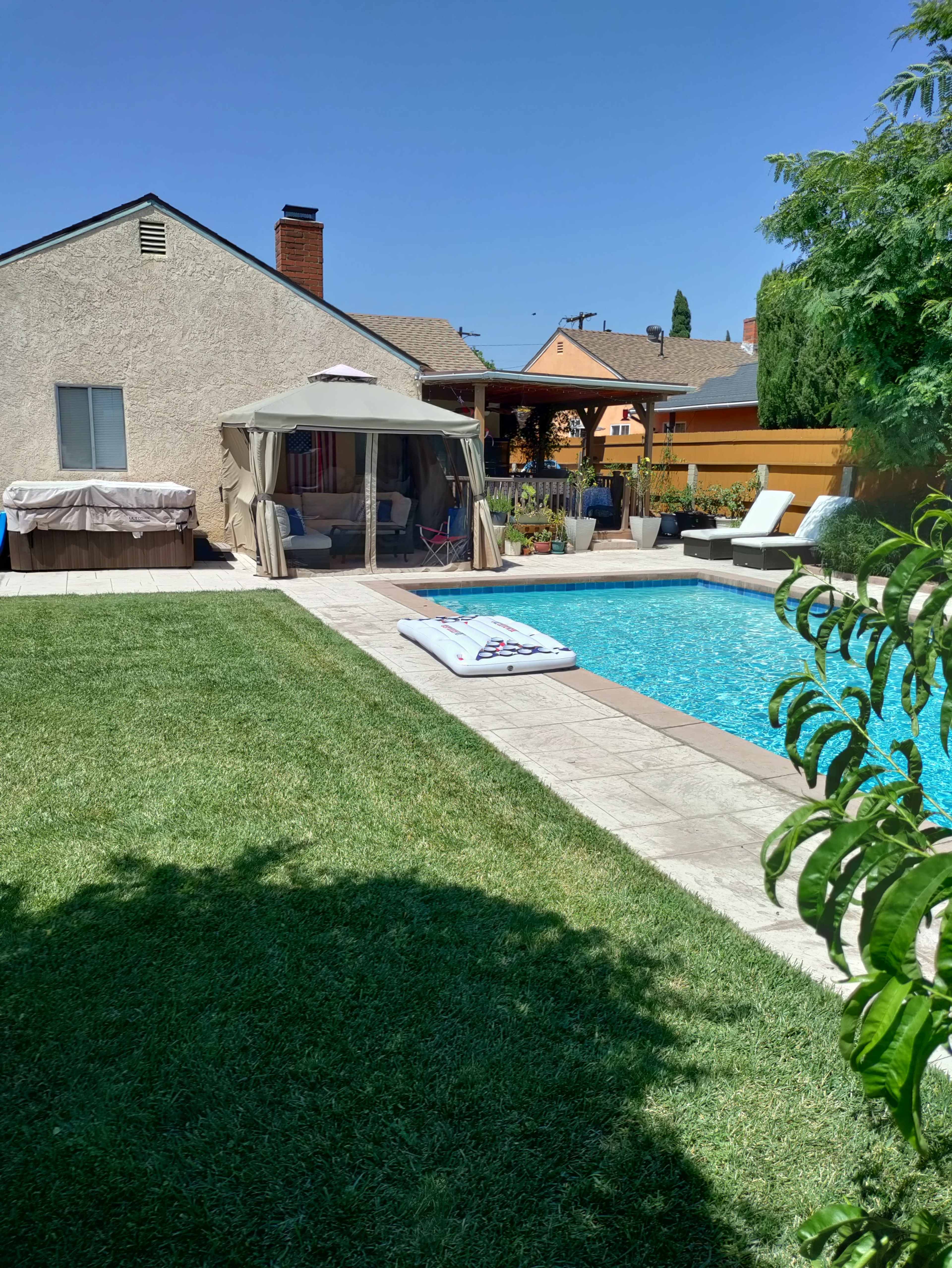 The image shows a backyard pool area featuring a swimming pool, a gazebo, lounge chairs, and a grassy lawn.
