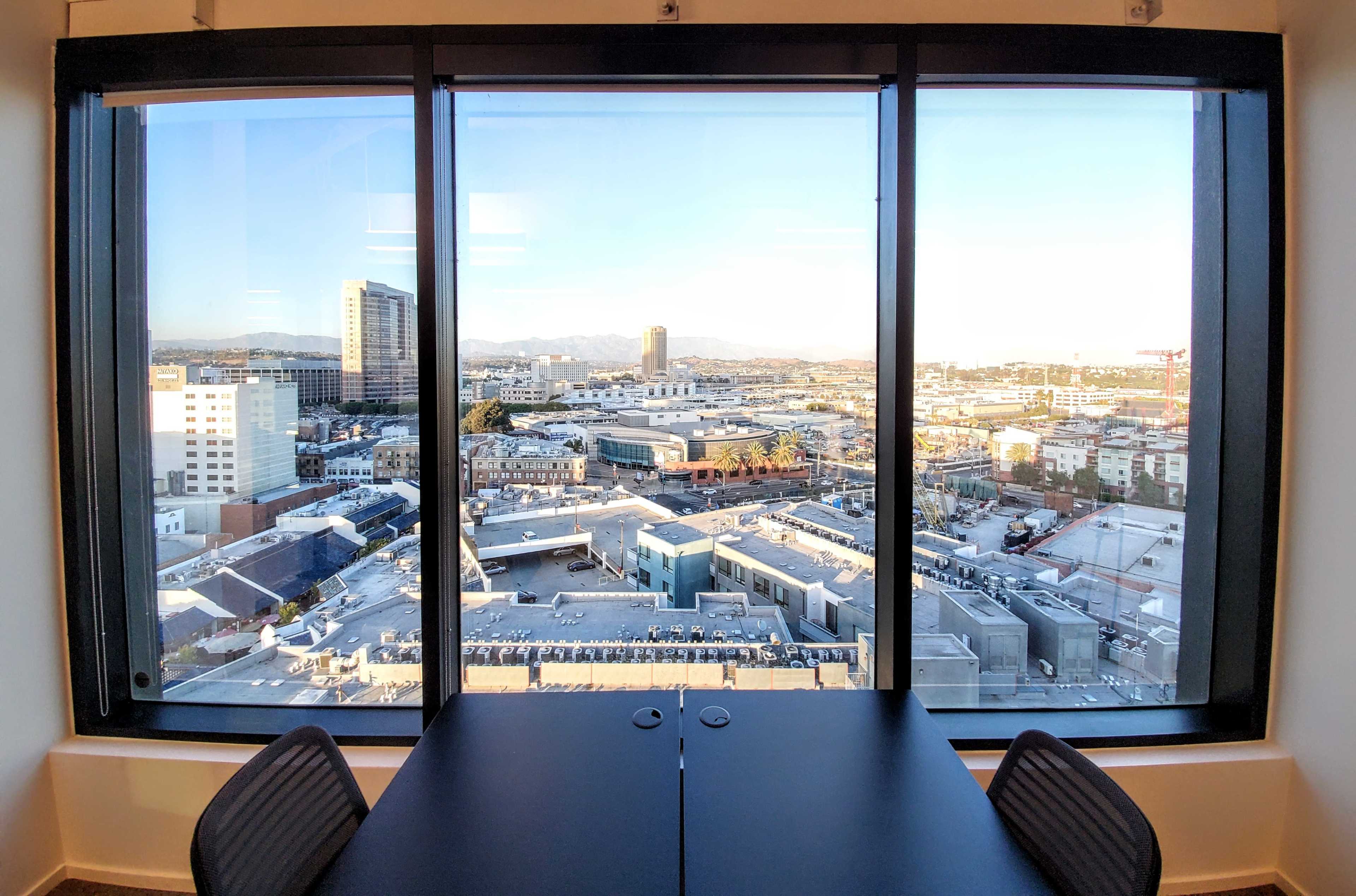 A large window view of a cityscape featuring buildings and rooftops under a clear sky.