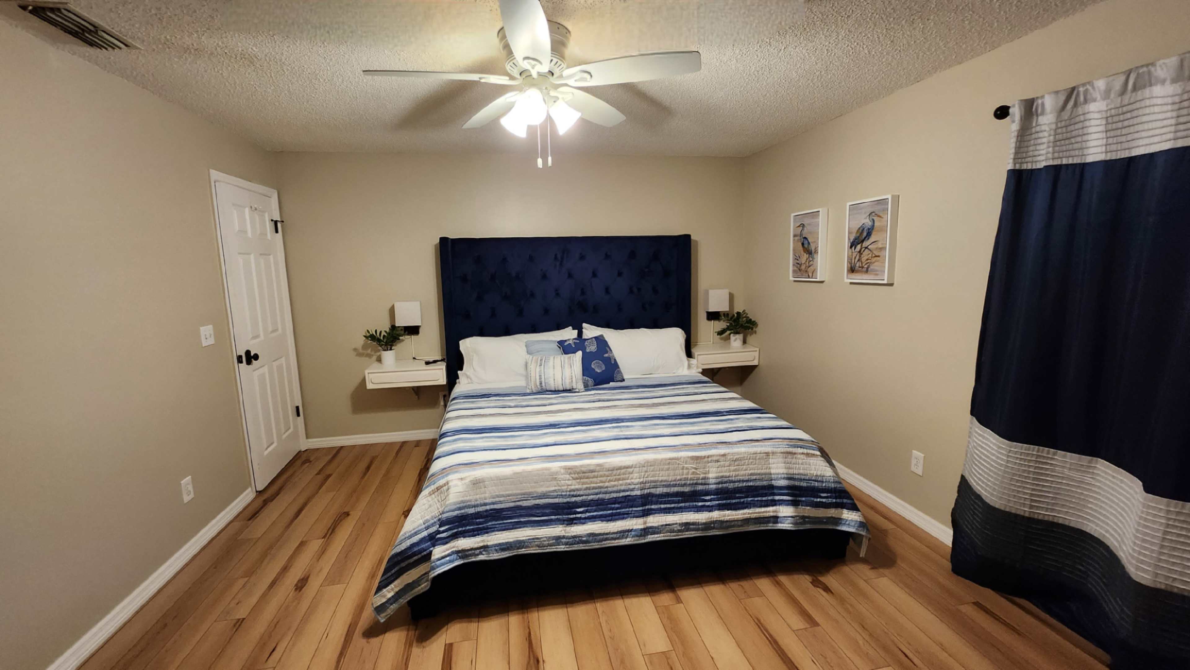 A neatly arranged bedroom featuring a blue and white striped bedspread, a tufted headboard, and two nightstands with lamps.
