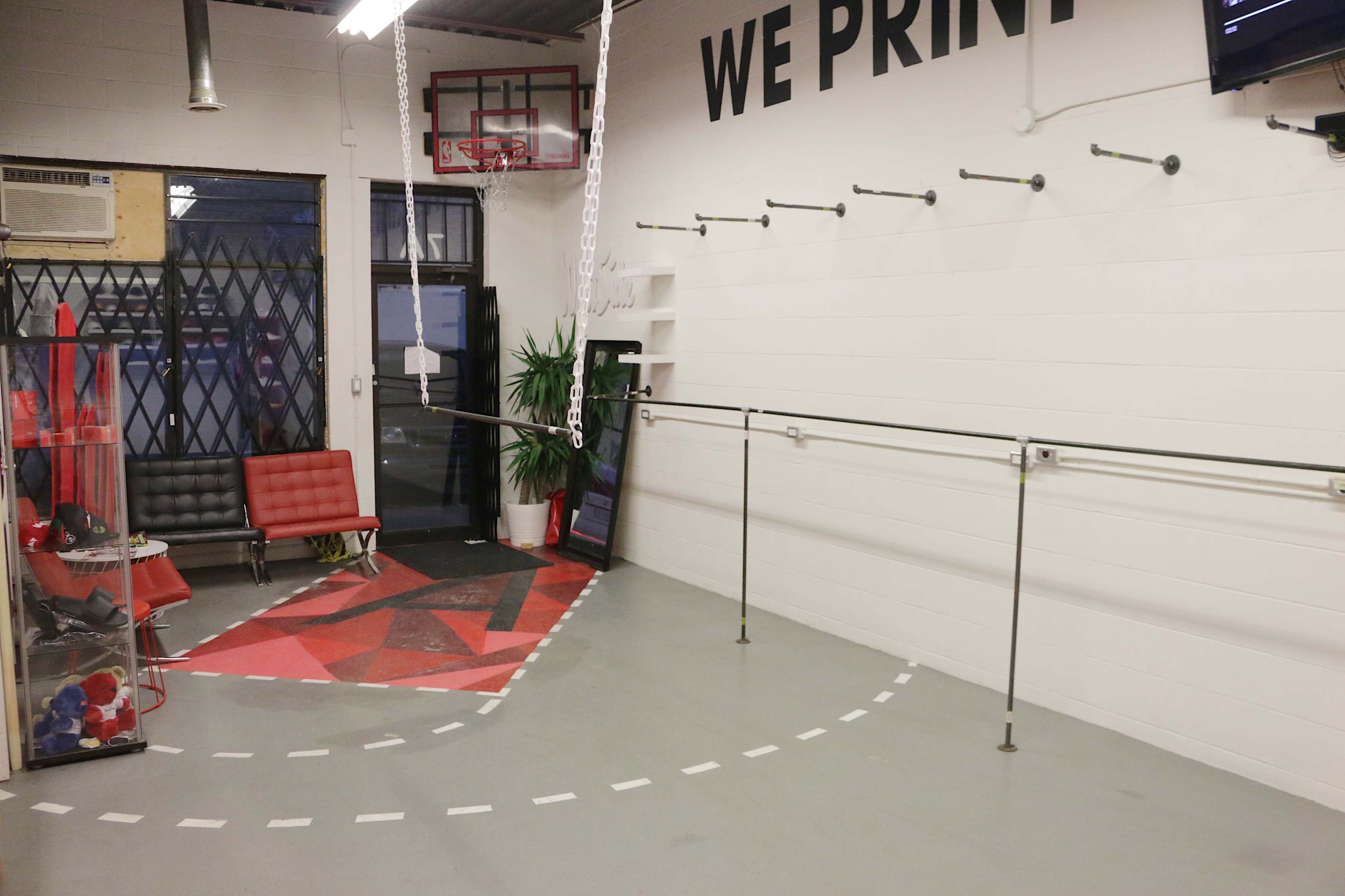 A spacious interior of a print shop featuring a red and black geometric floor design, a bench, and wall-mounted equipment.