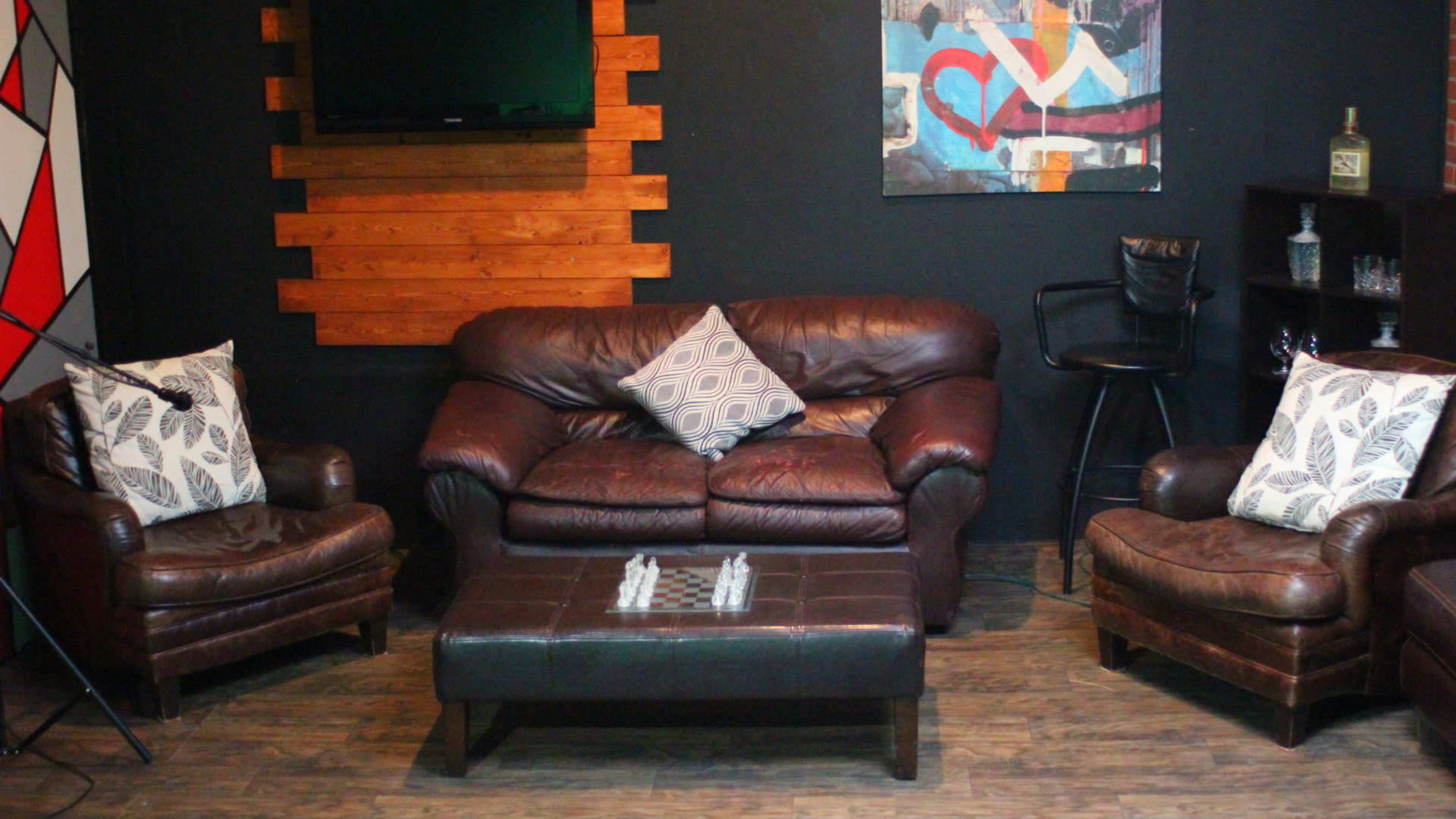 A cozy seating area features a leather couch and chairs arranged around a coffee table with a chessboard.