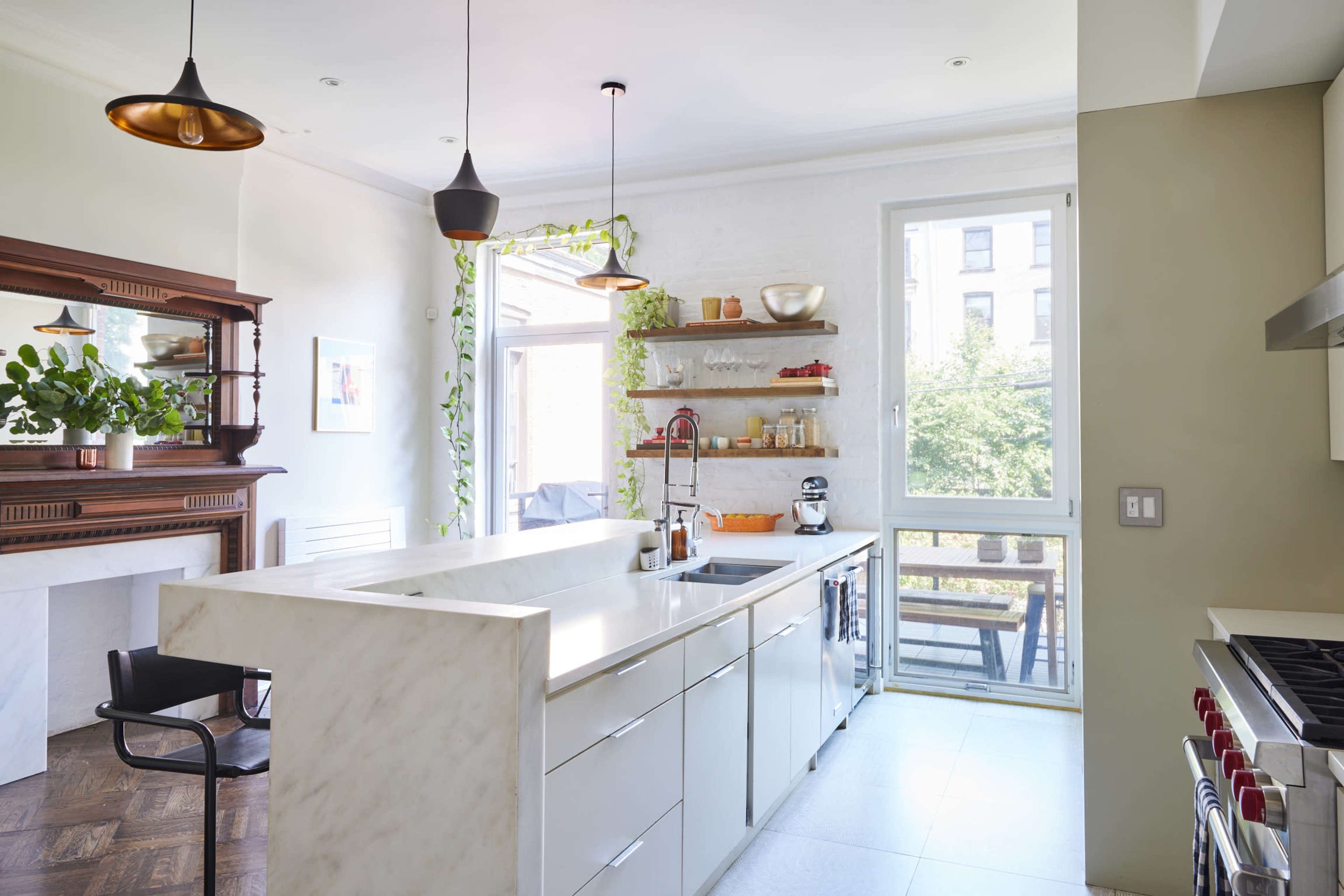 The kitchen features a white marble countertop, modern cabinetry, a window overlooking a patio, and a mix of contemporary and classic design elements.