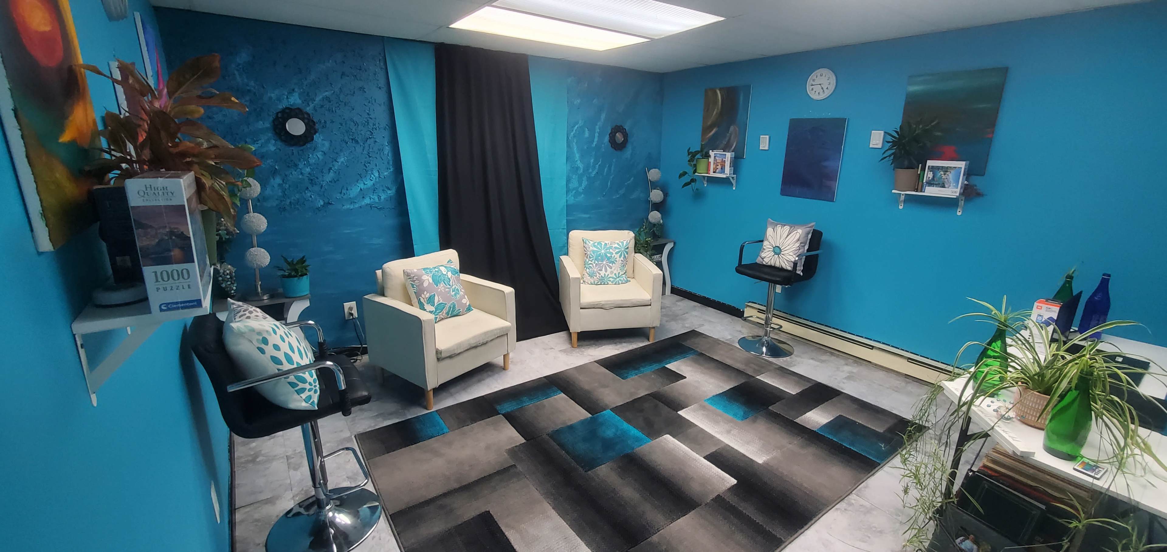 A bright blue room with two white chairs and a bar stool, a patterned rug, and various wall decorations, including plants and shelves.