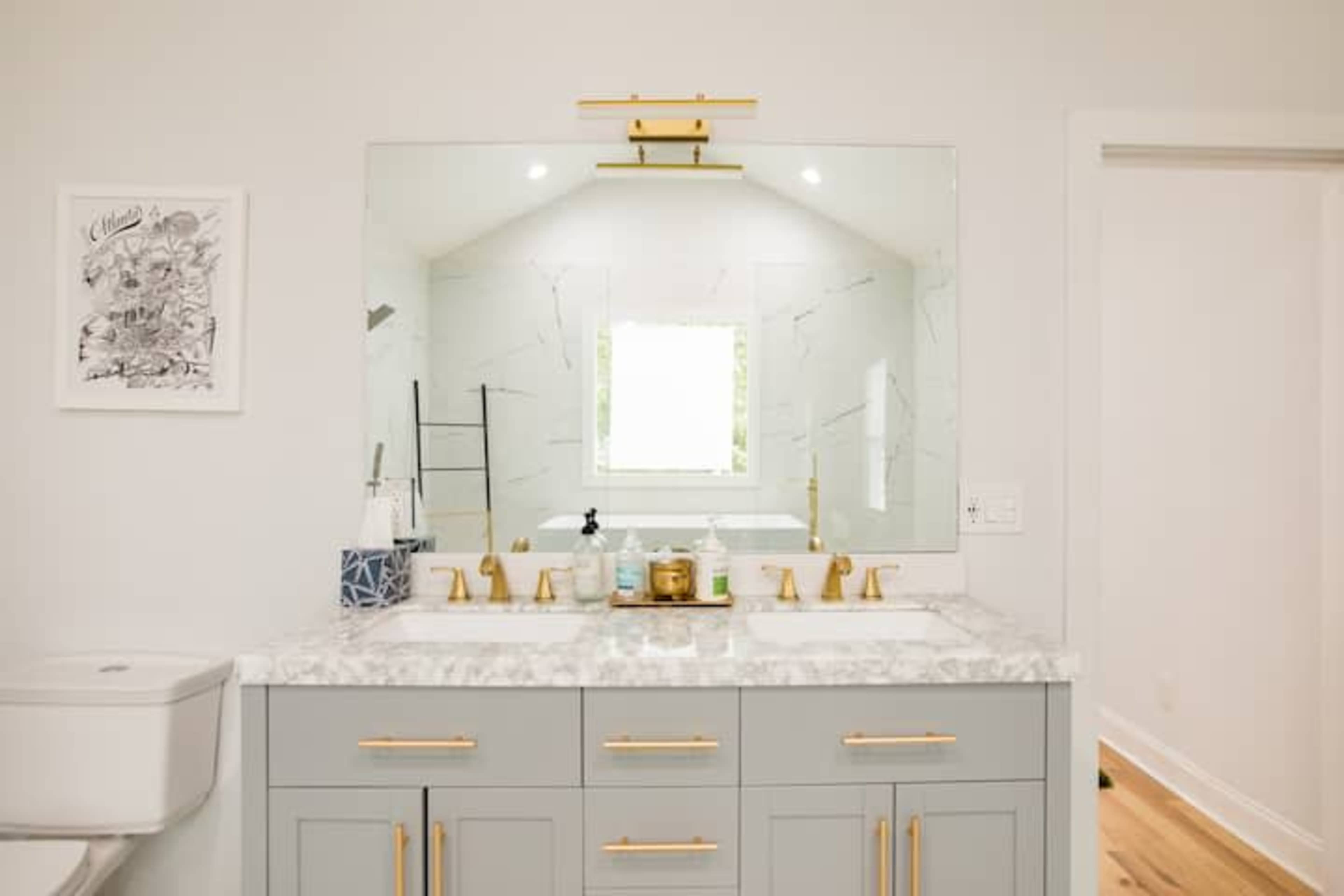 A modern bathroom with a double sink vanity, a large mirror, and a window providing natural light.