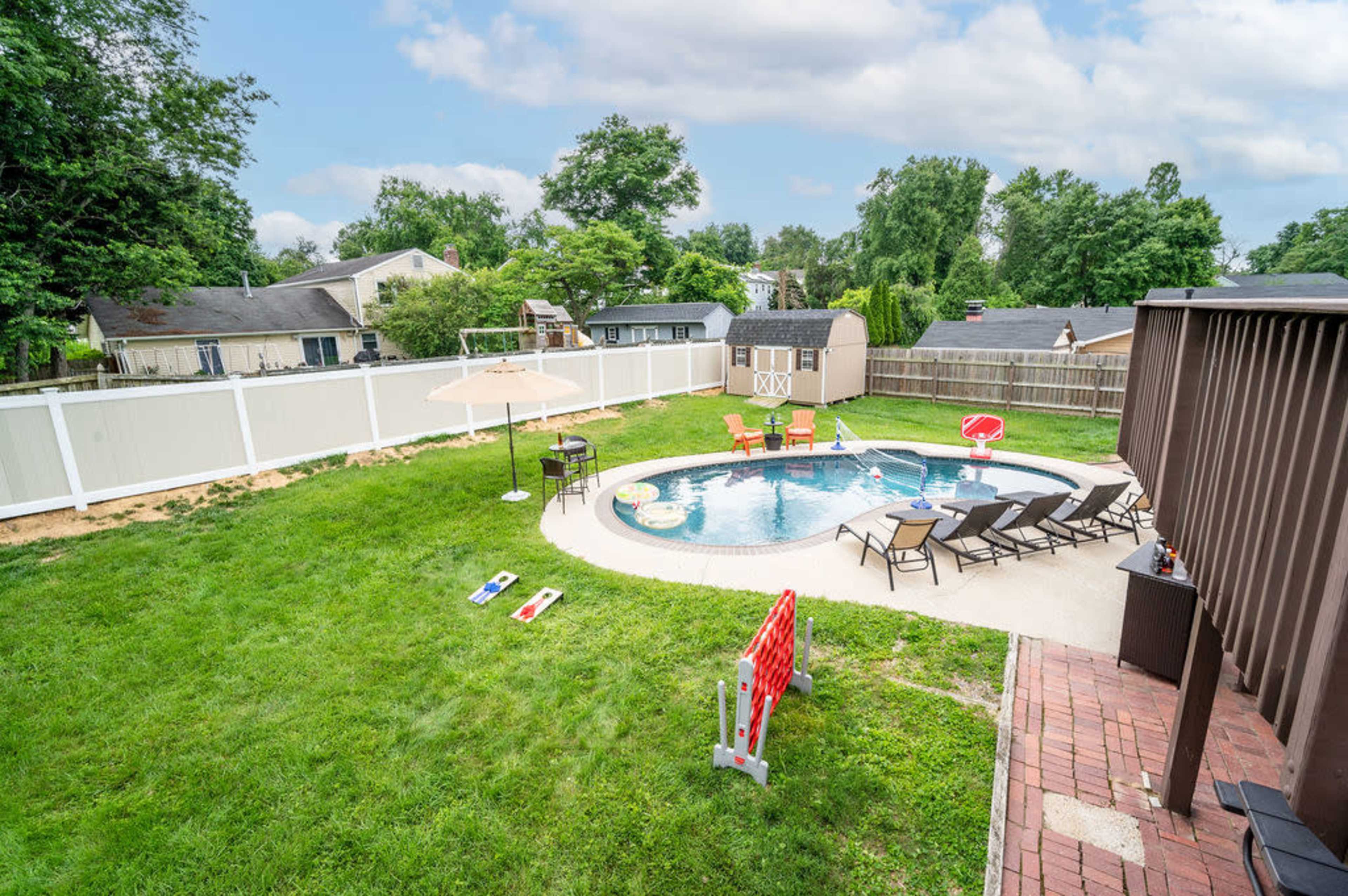 A spacious backyard with a swimming pool, lounge chairs, and nearby recreational equipment.