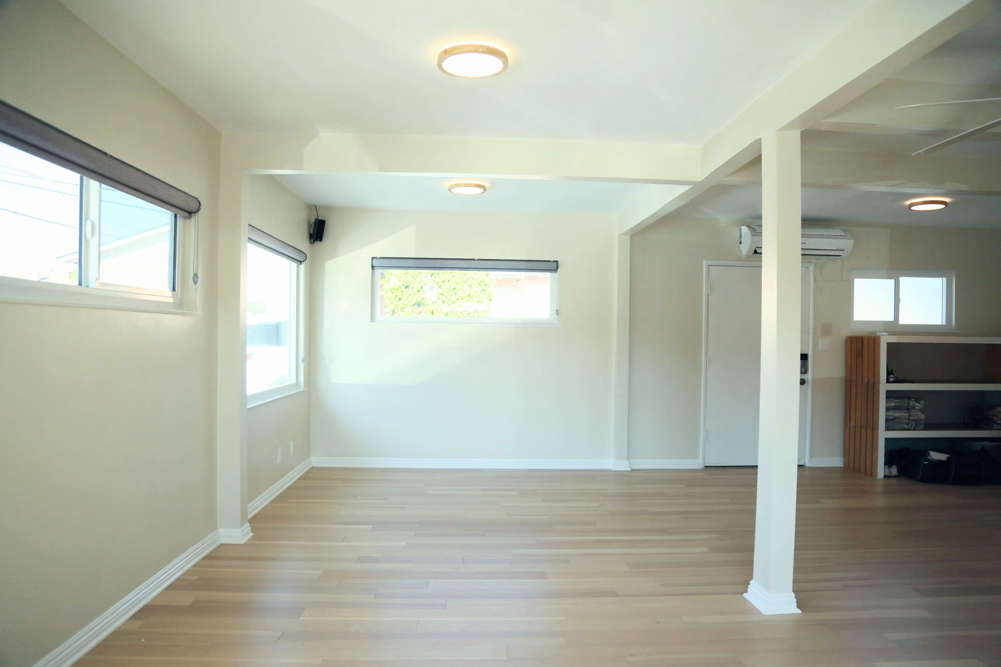The room features light-colored walls, a wooden floor, and multiple windows that allow natural light to enter.