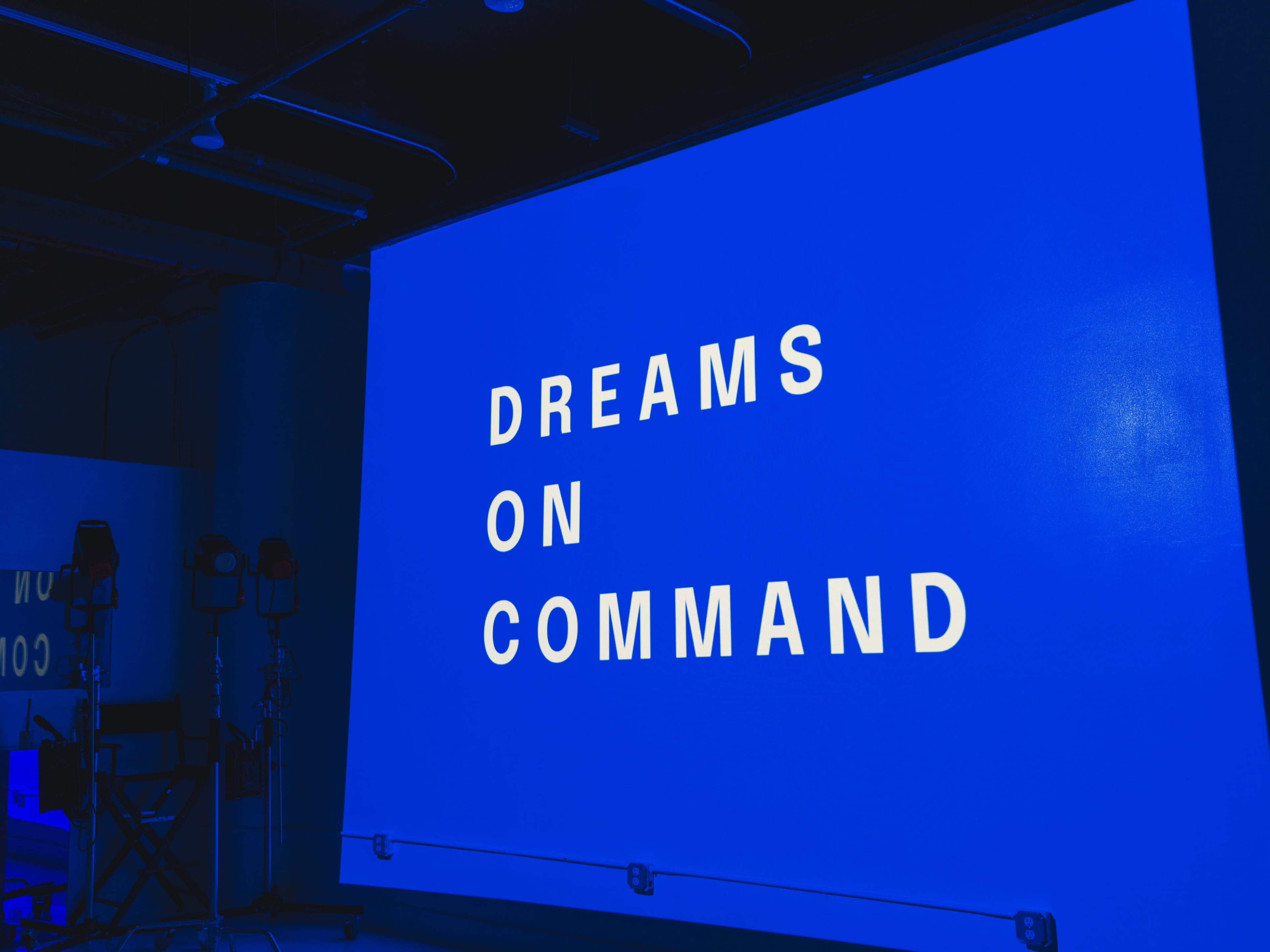 A large blue screen displays the phrase "DREAMS ON COMMAND" in bold white letters.