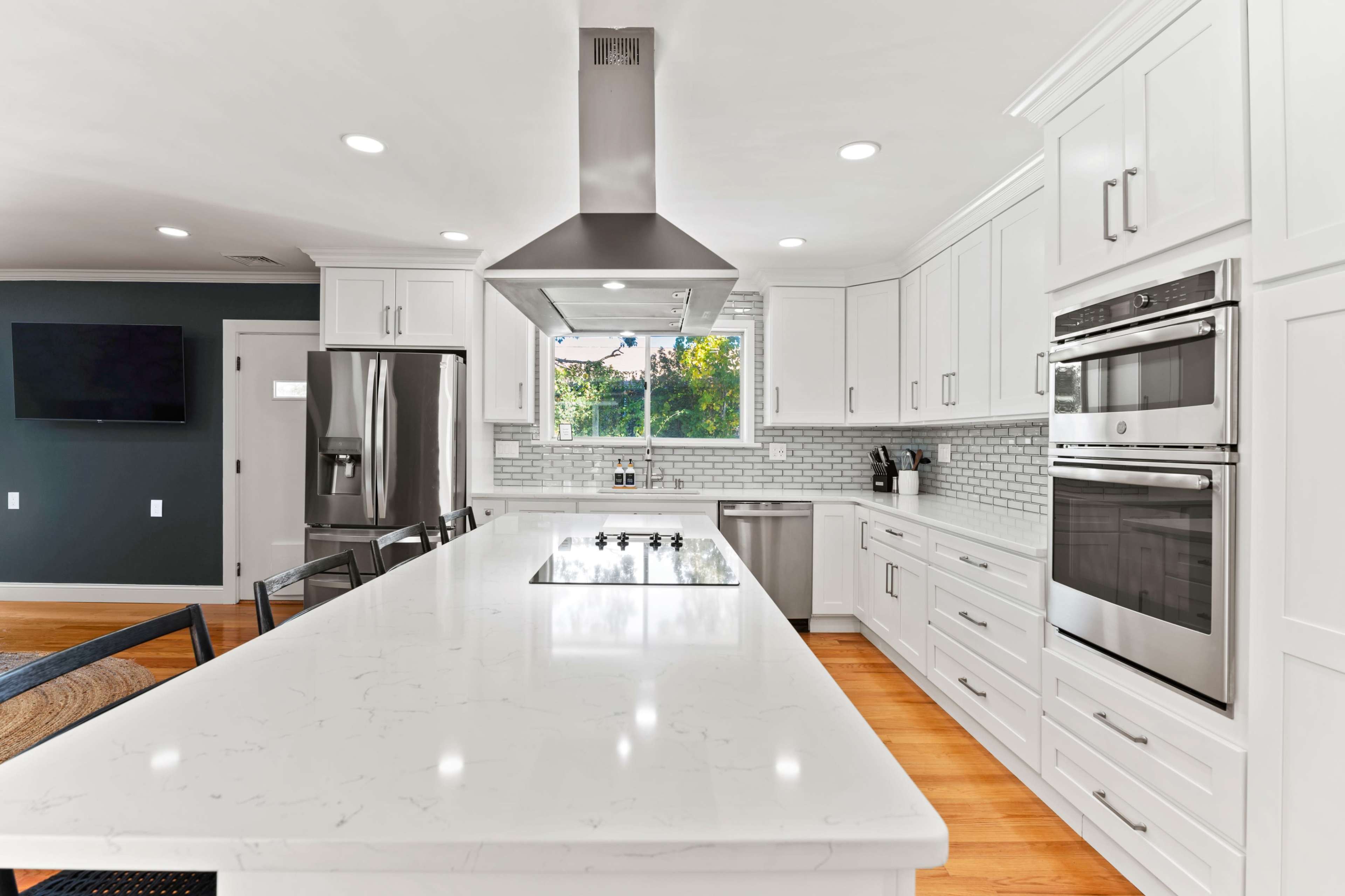 A modern kitchen featuring white cabinetry, stainless steel appliances, and a large island with a cooktop and seating.
