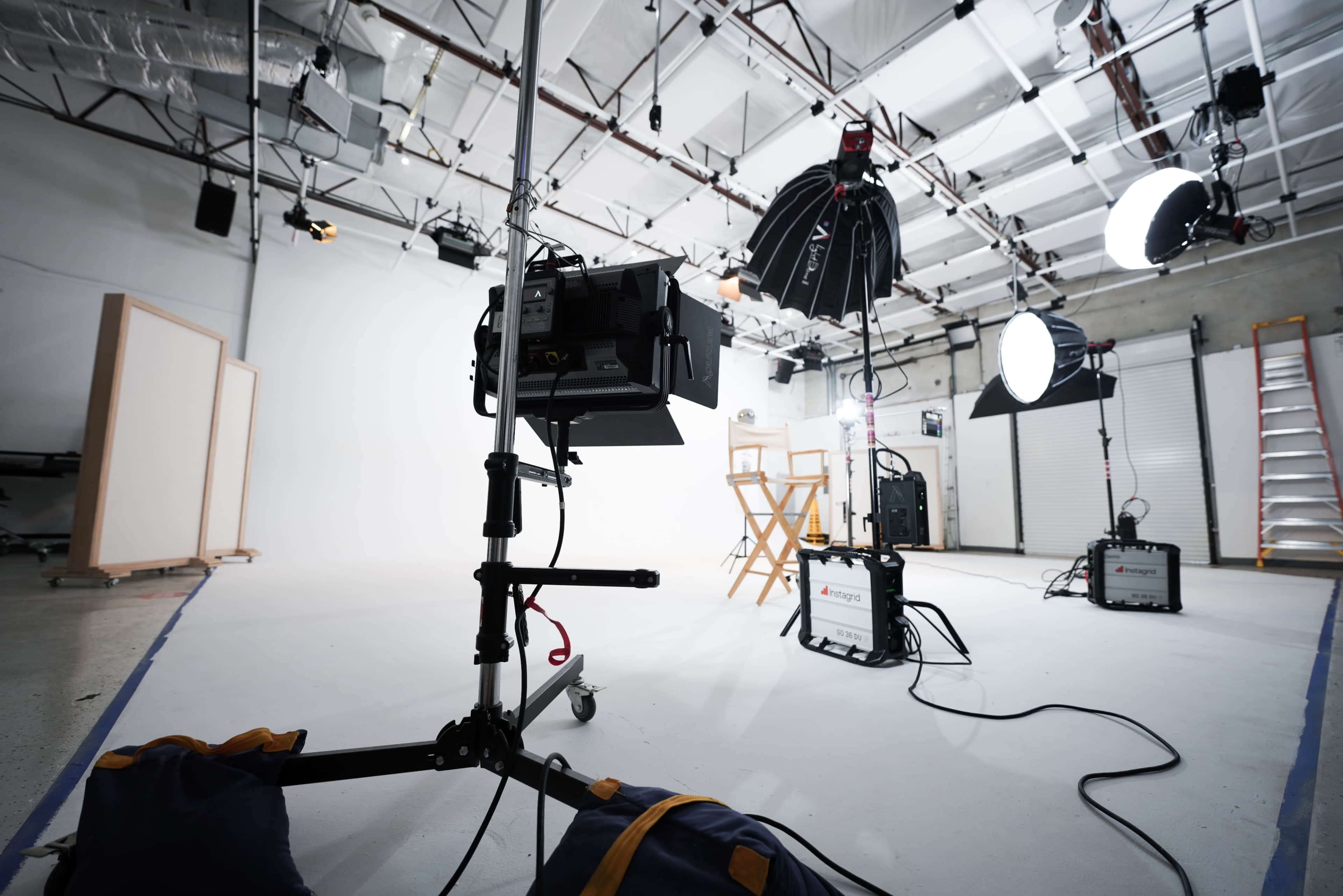 The image shows a photography studio setup with lighting equipment, a director's chair, and a backdrop.