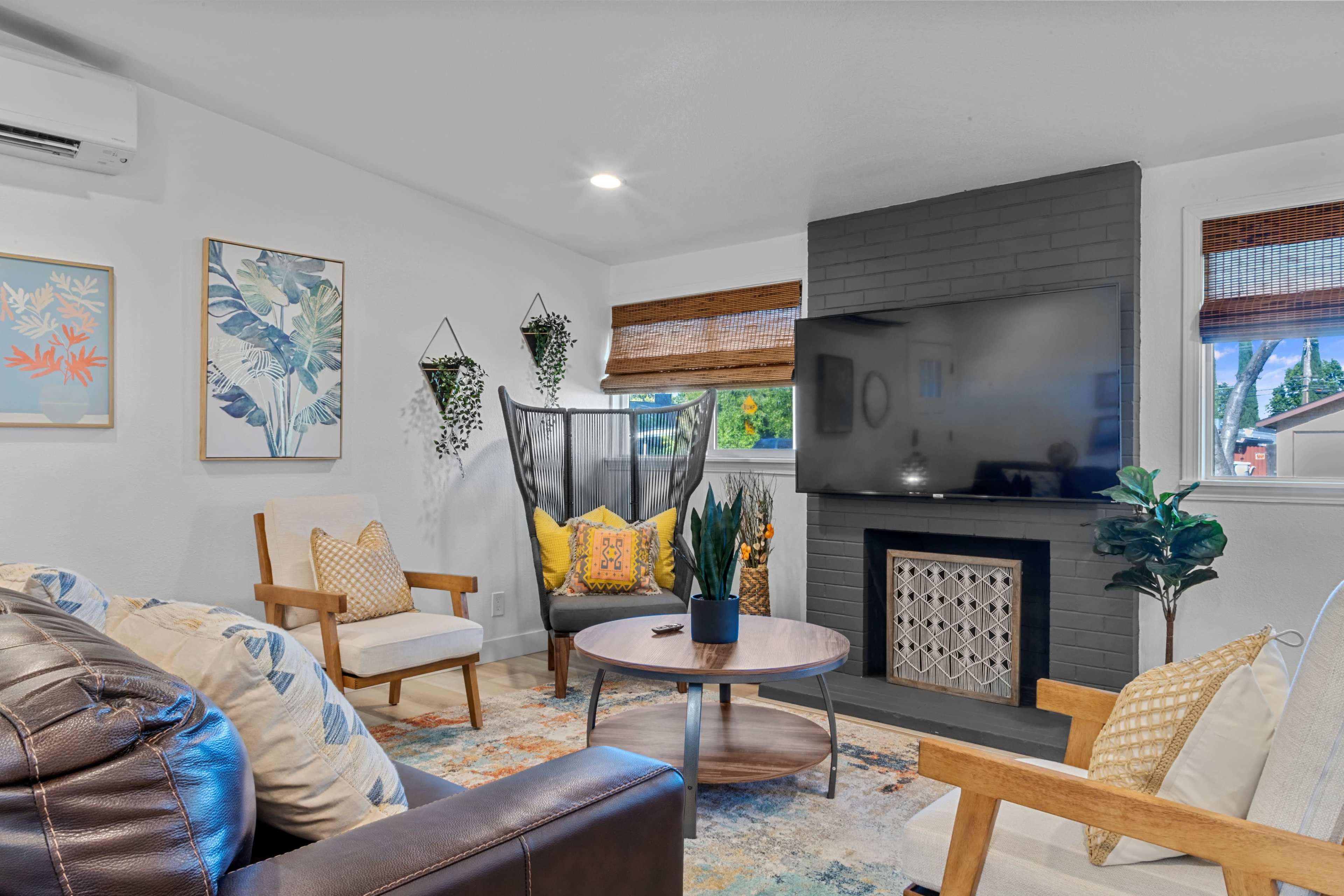 A modern living room featuring a black fireplace, a round coffee table, and comfortable seating arrangements with decorative pillows.