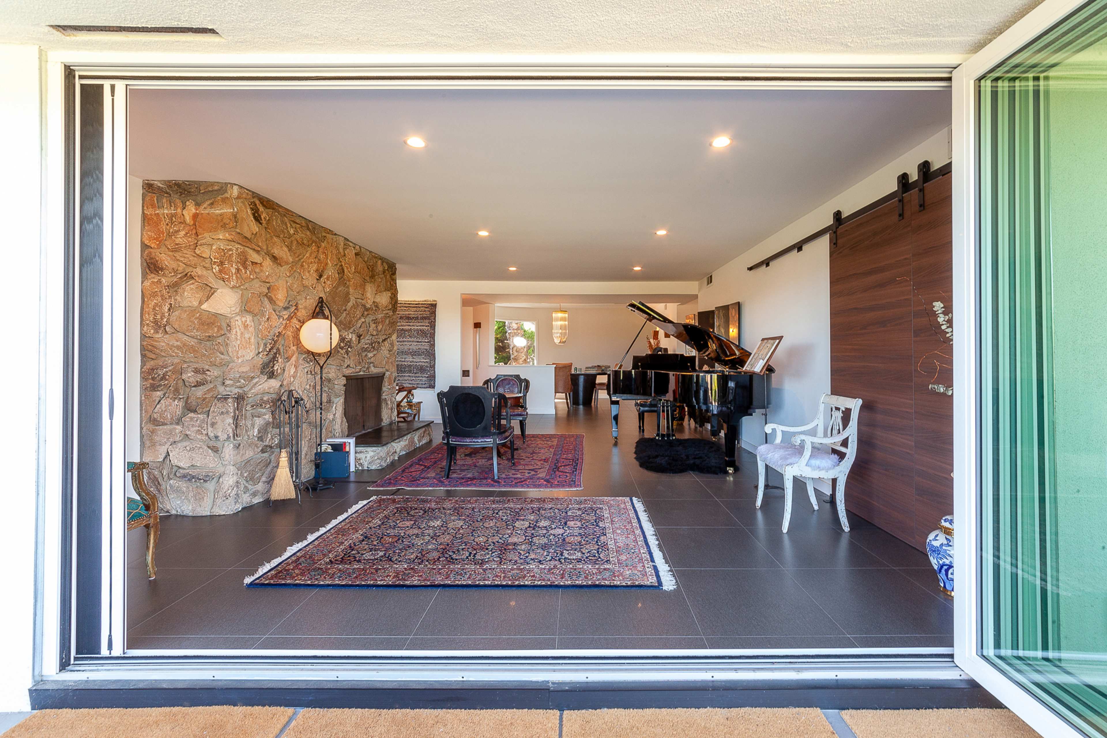 A spacious living area features a grand piano, elegant seating, and a stone accent wall.