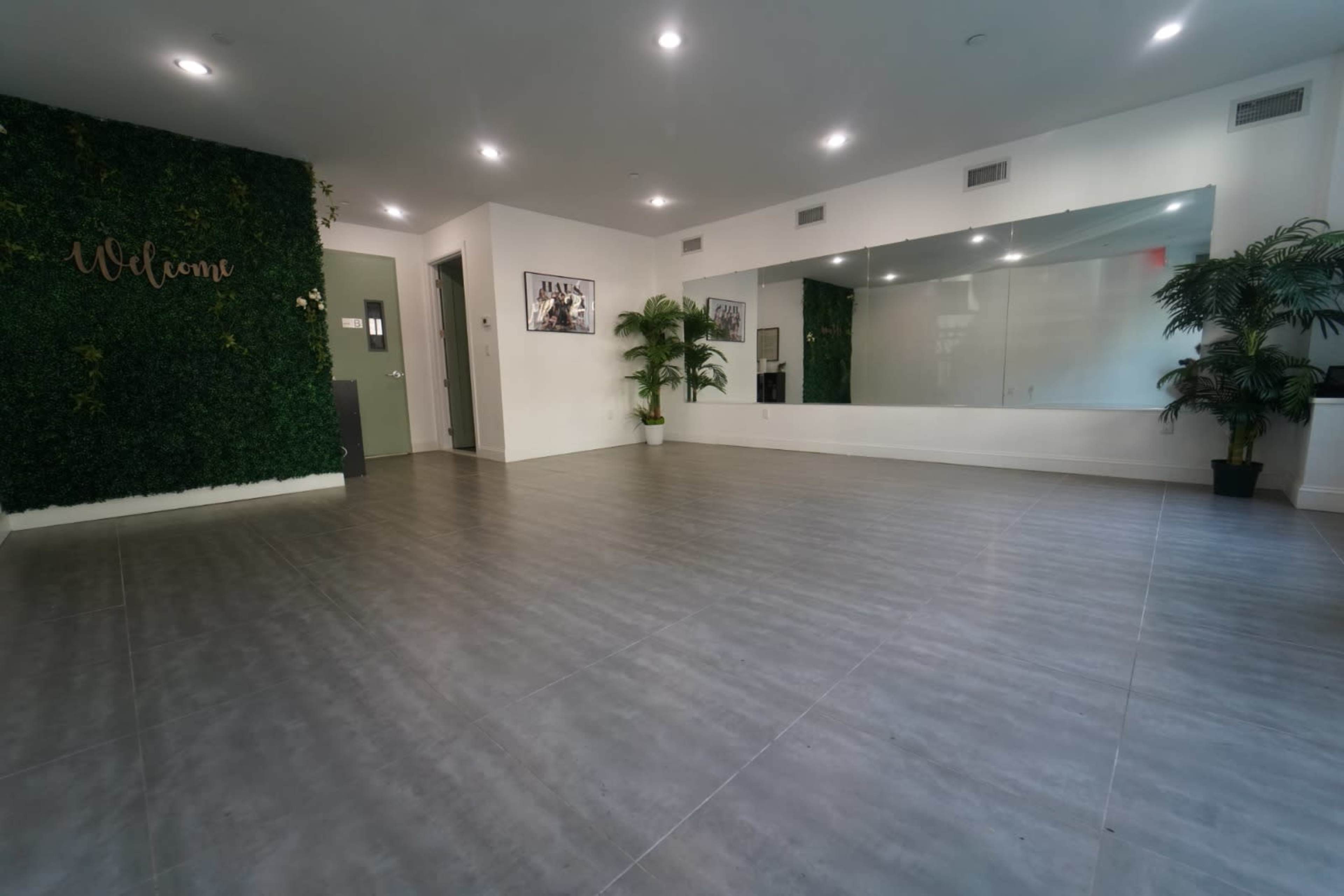 A spacious interior with a mirrored wall, greenery, and modern tile flooring.