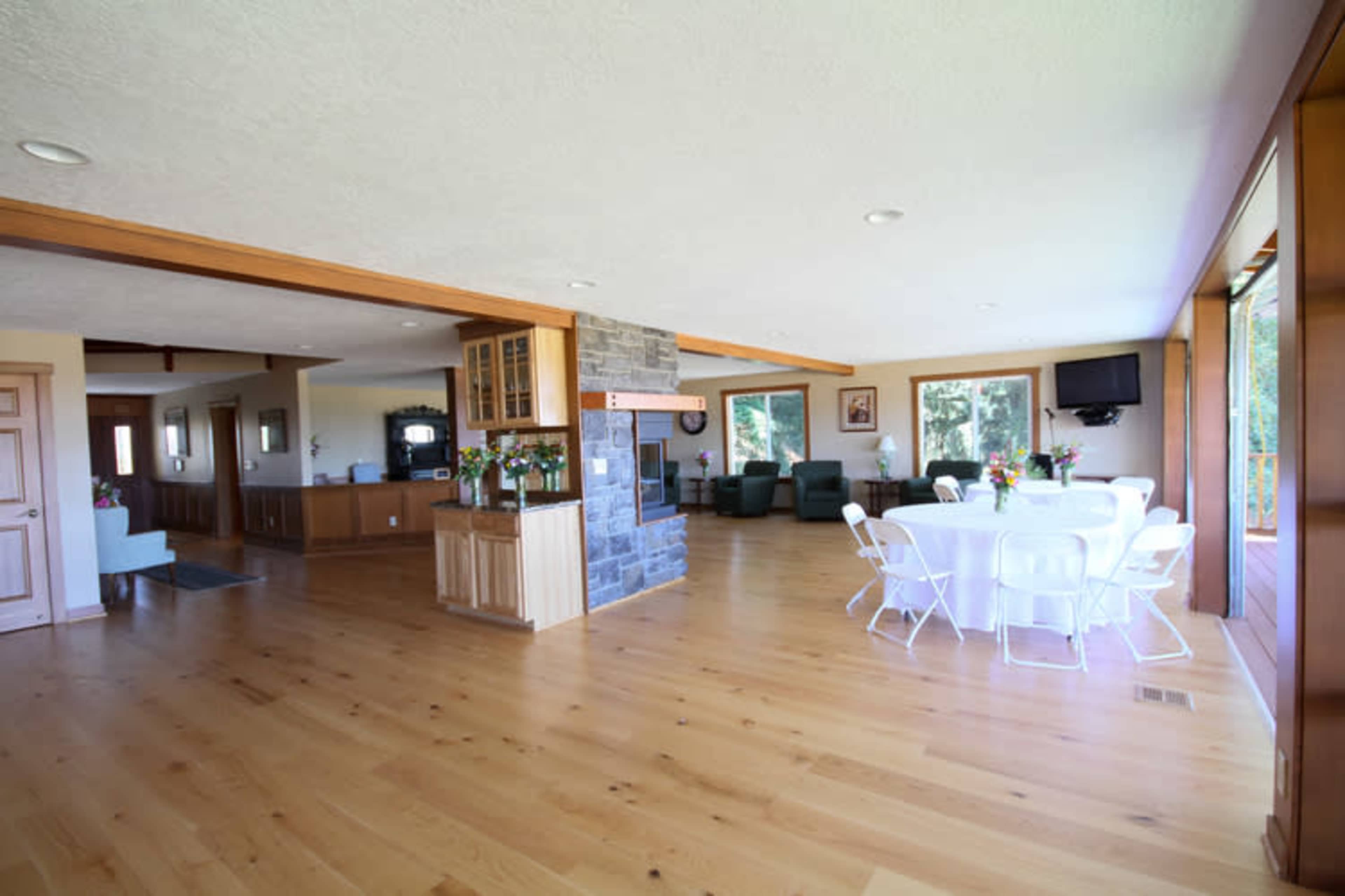 The interior features an open-layout space with a dining area set for eight and a cozy seating area with green chairs.