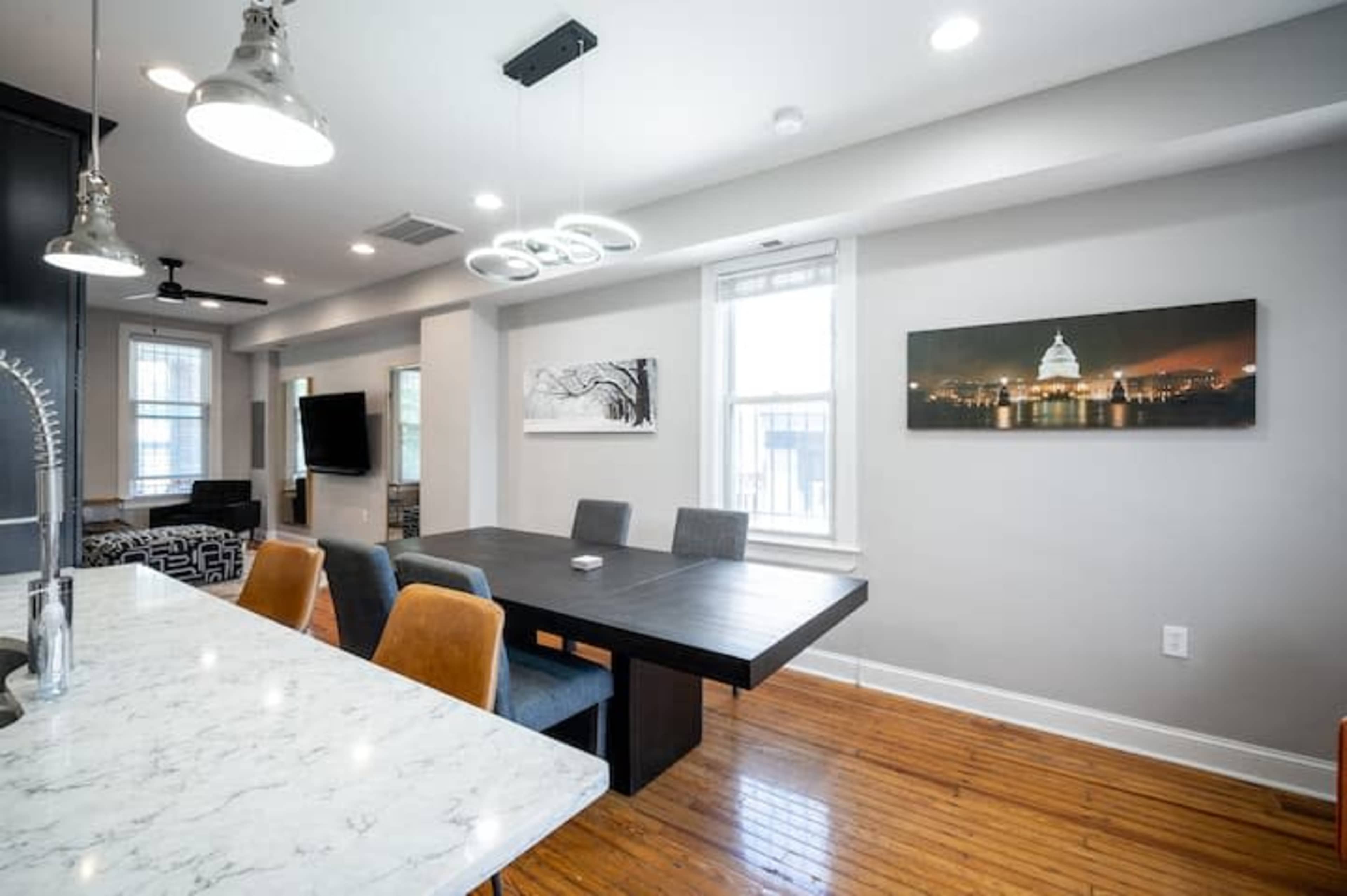 A modern dining area with a wooden table, surrounding chairs, and a view of a cityscape on the wall.