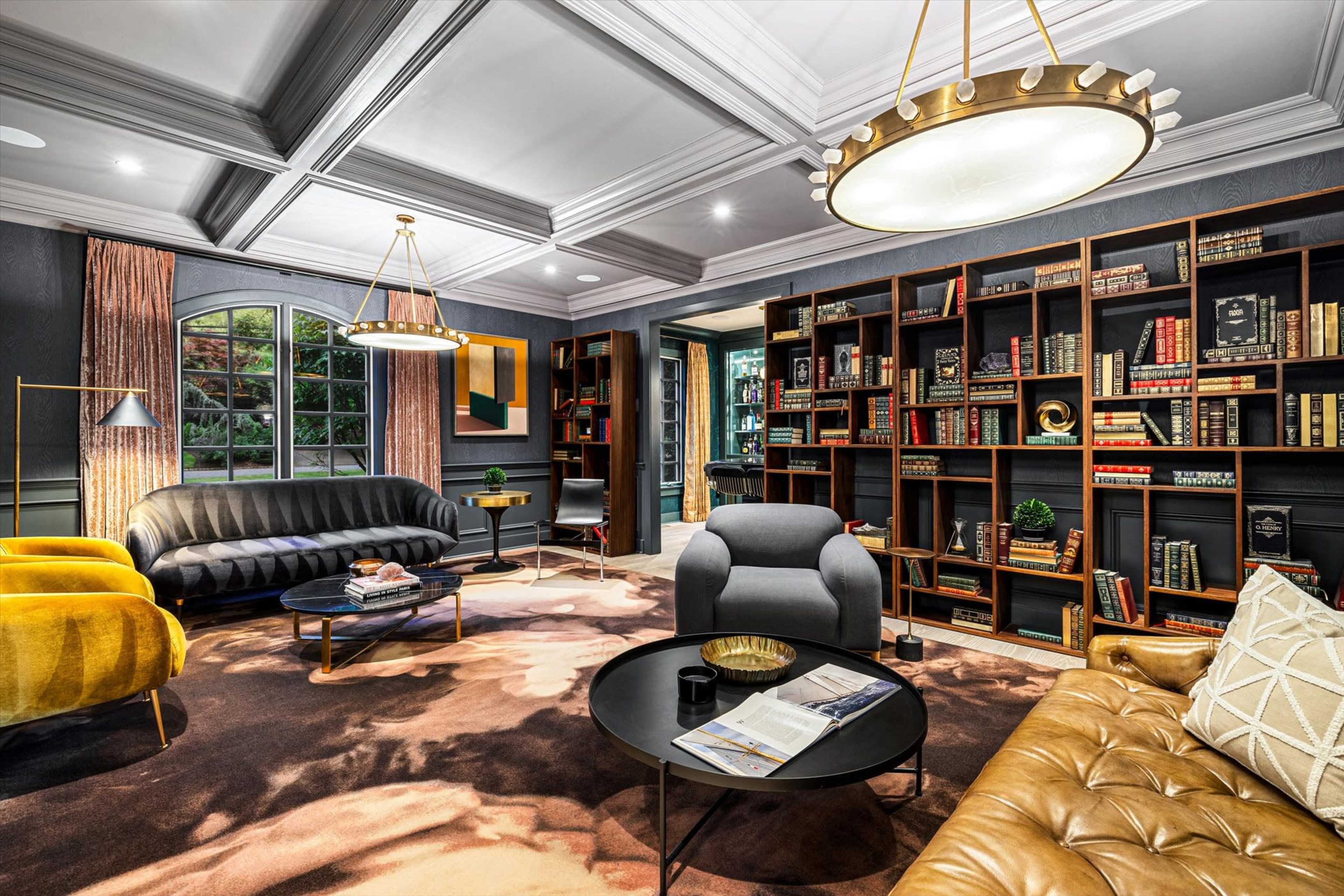 The image depicts a stylish living room featuring a mix of modern furniture, a large bookshelf filled with books, and decorative lighting.